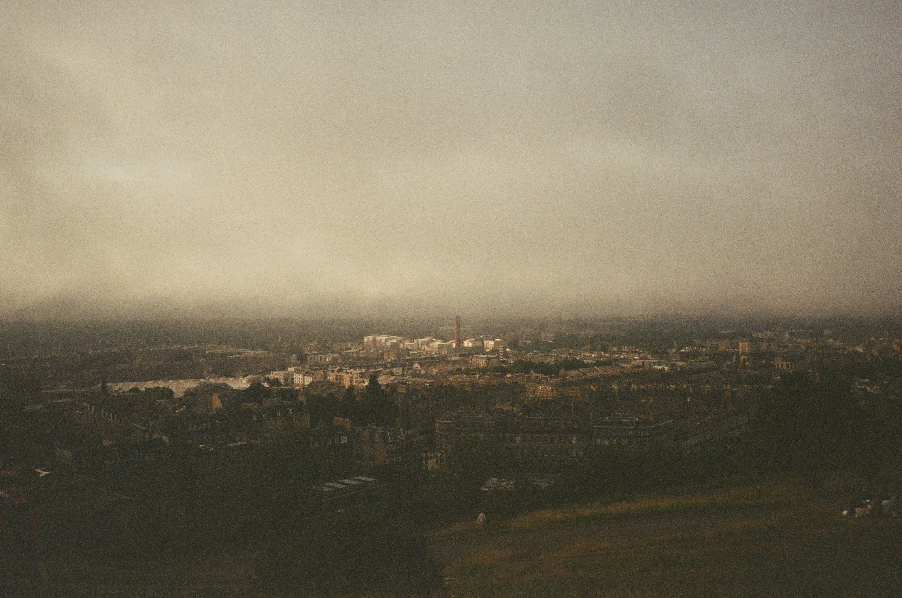 Misty cityscape with distant lights under cloudy sky