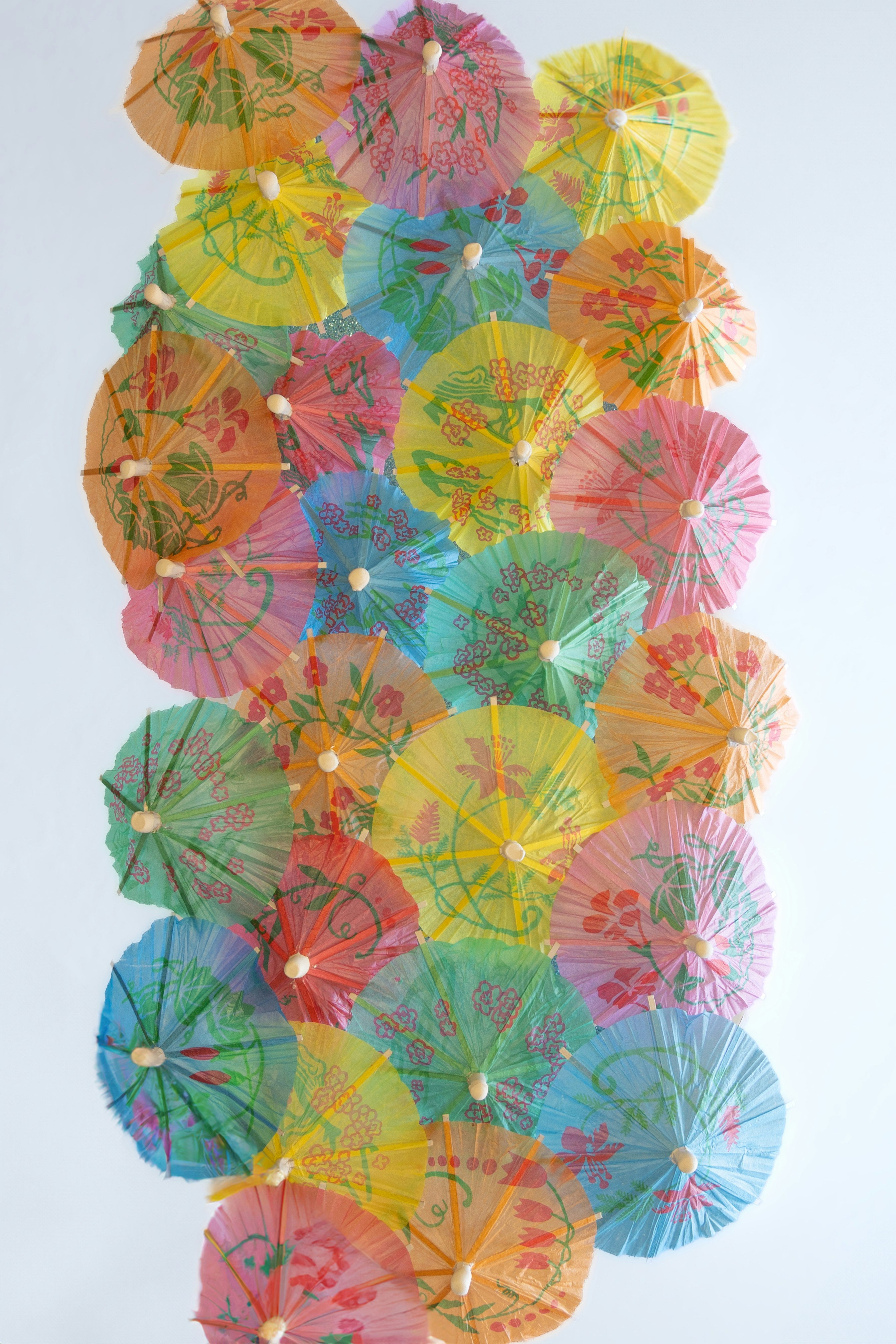 Colorful cocktail umbrellas arranged vertically on a white background.