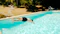 Man dives into a bright blue swimming pool.