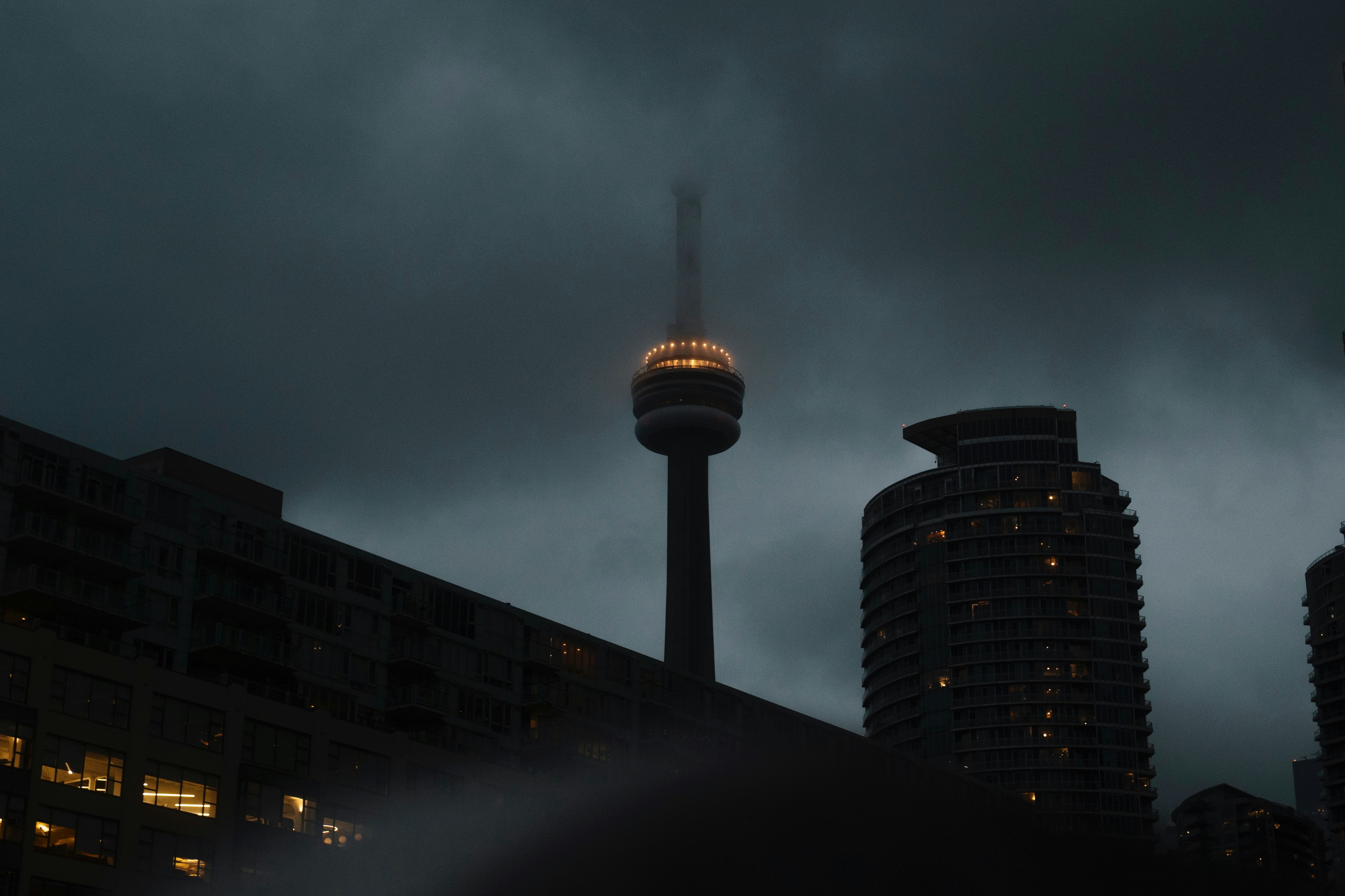 Tall tower illuminated against a dark, cloudy sky.