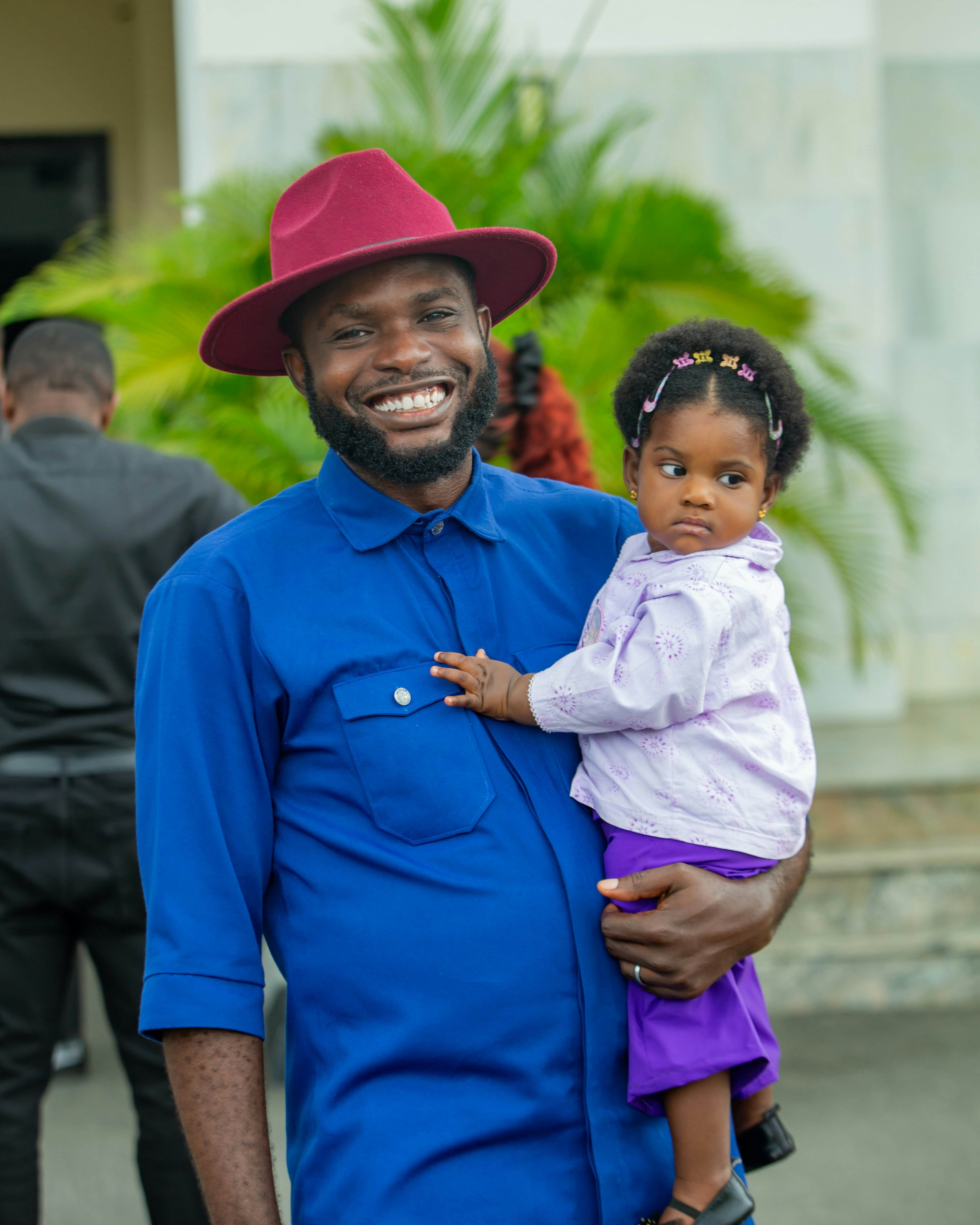 Pria berbaju biru dan topi merah menggendong bayi