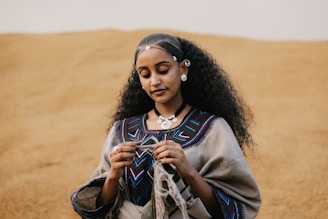 Ethiopian Silver Jewellery Through Time Woman in traditional clothing holds yarn in desert
