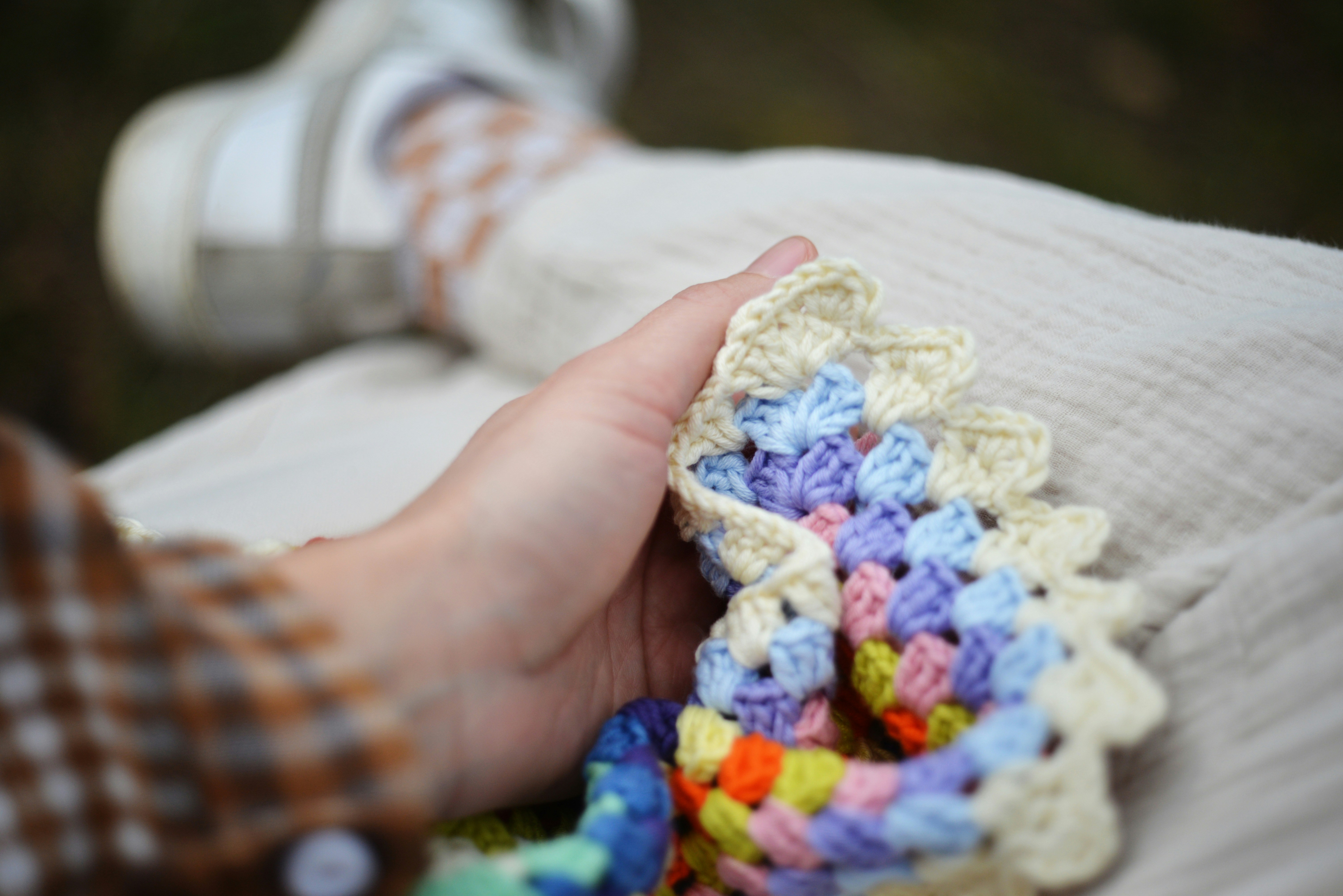 Person holding colorful crochet blanket with textured fabric