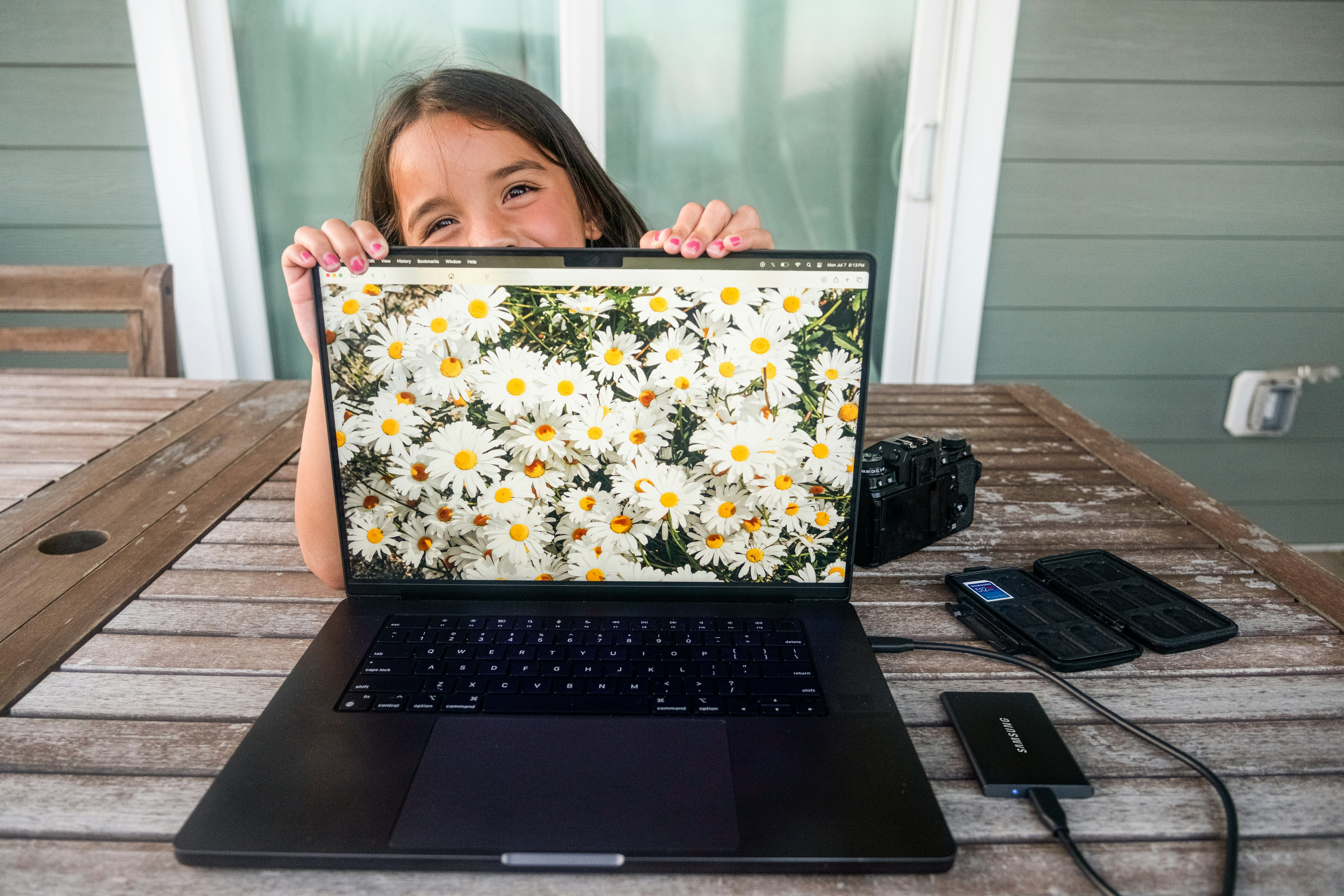 Girl peeking over laptop with daisies