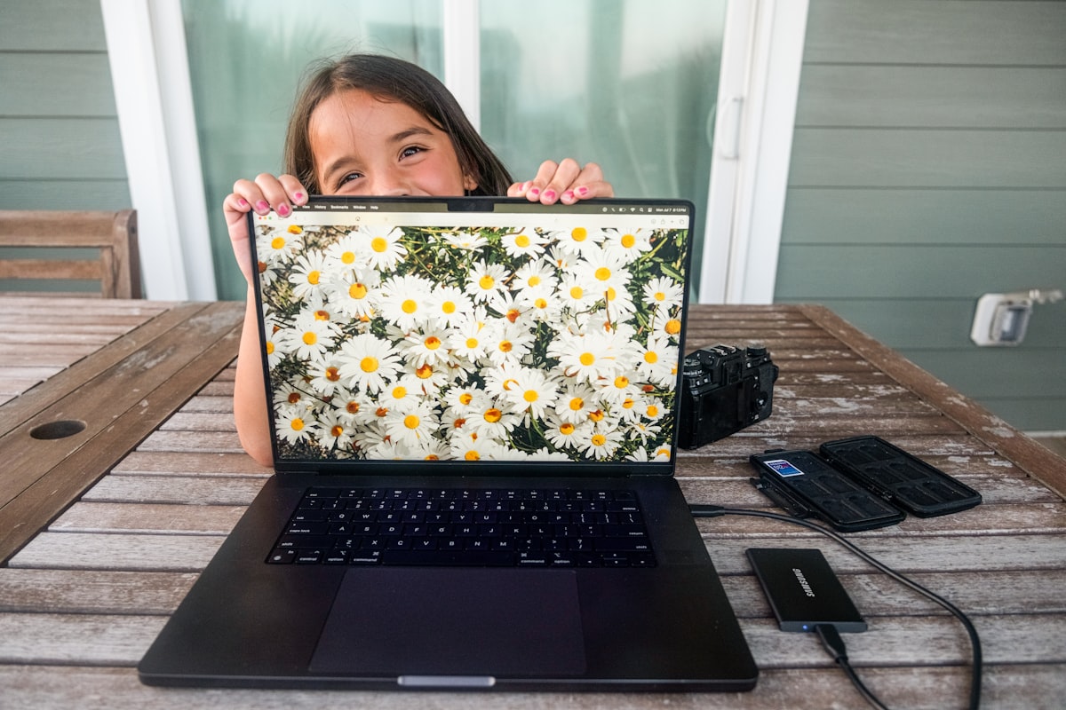 A woman working on a laptop in a rural setting with daisies