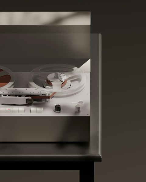 A vintage reel-to-reel tape recorder with its lid open, representing recording a production run once and replaying it on demand
