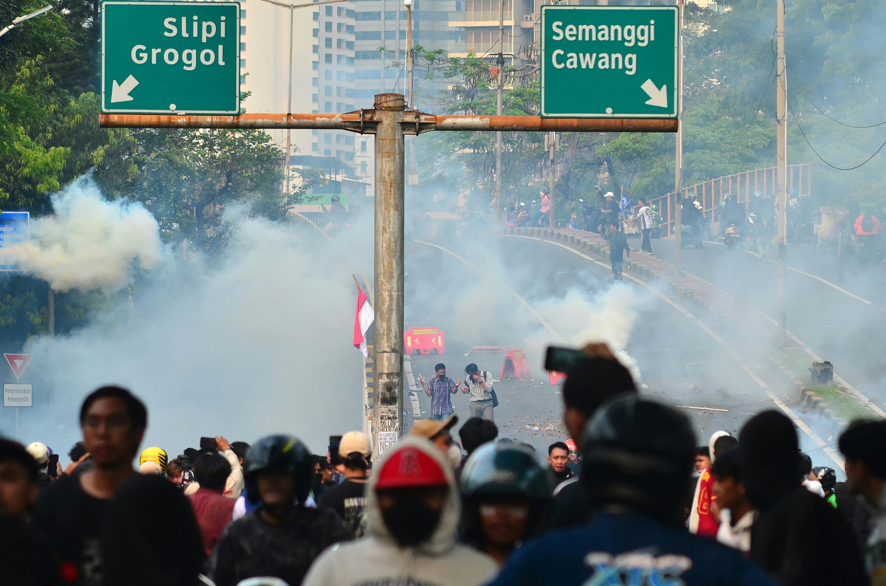 Crowd with smoke under highway signs