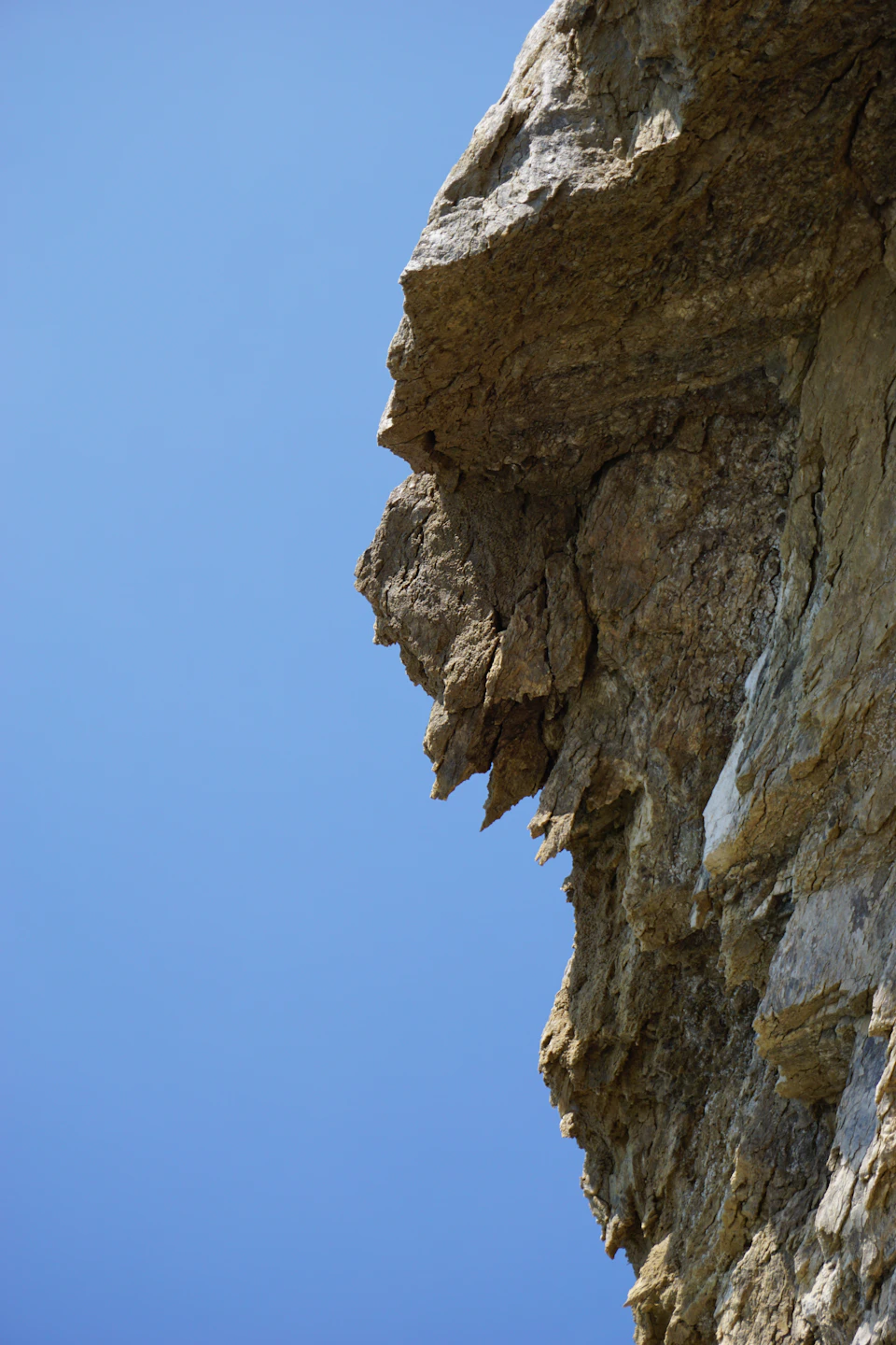 Large, jagged rock face with prominent crevice and contrasting smooth surfaces in landscape