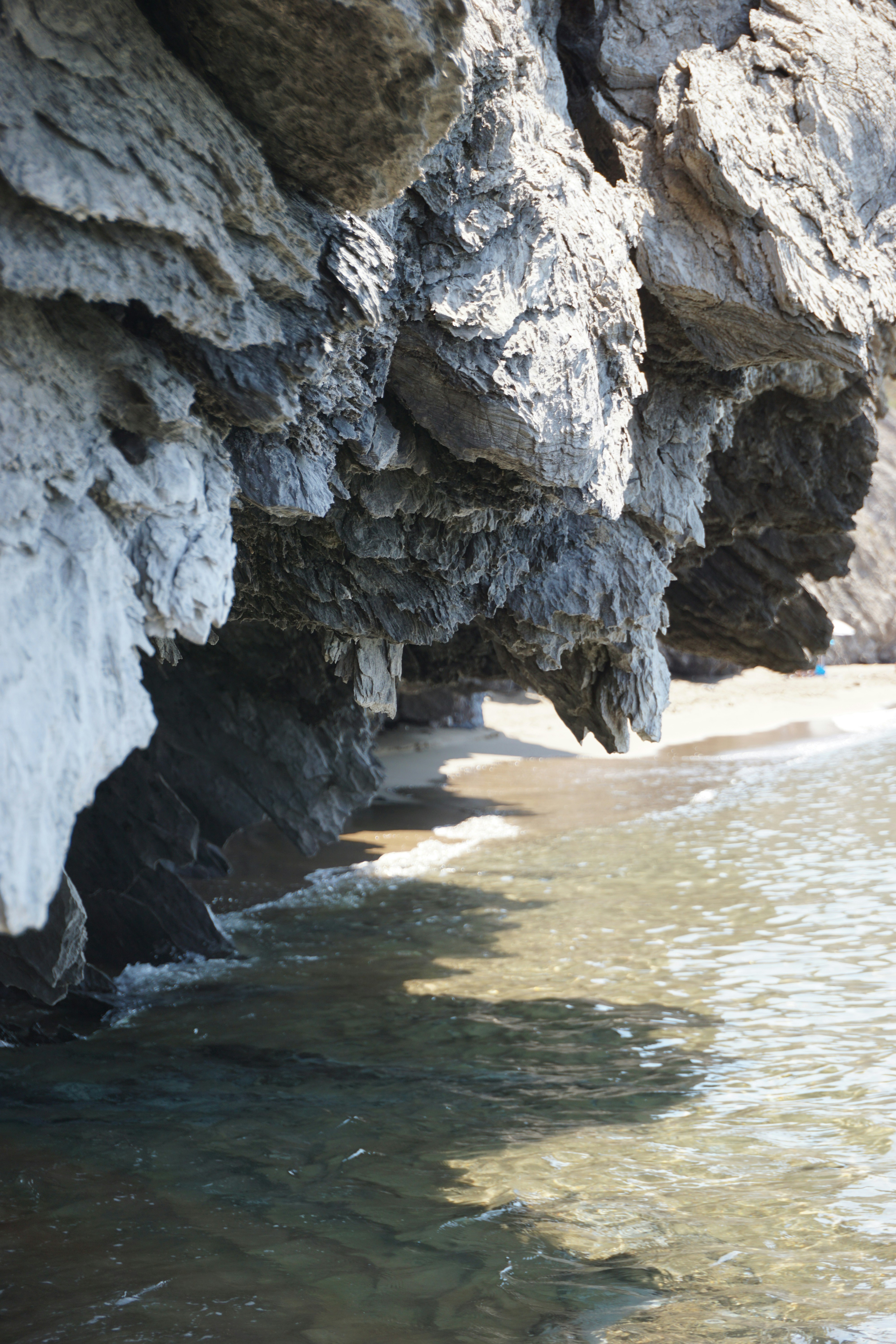 Rocky cliff overhangs above a calm, clear ocean
