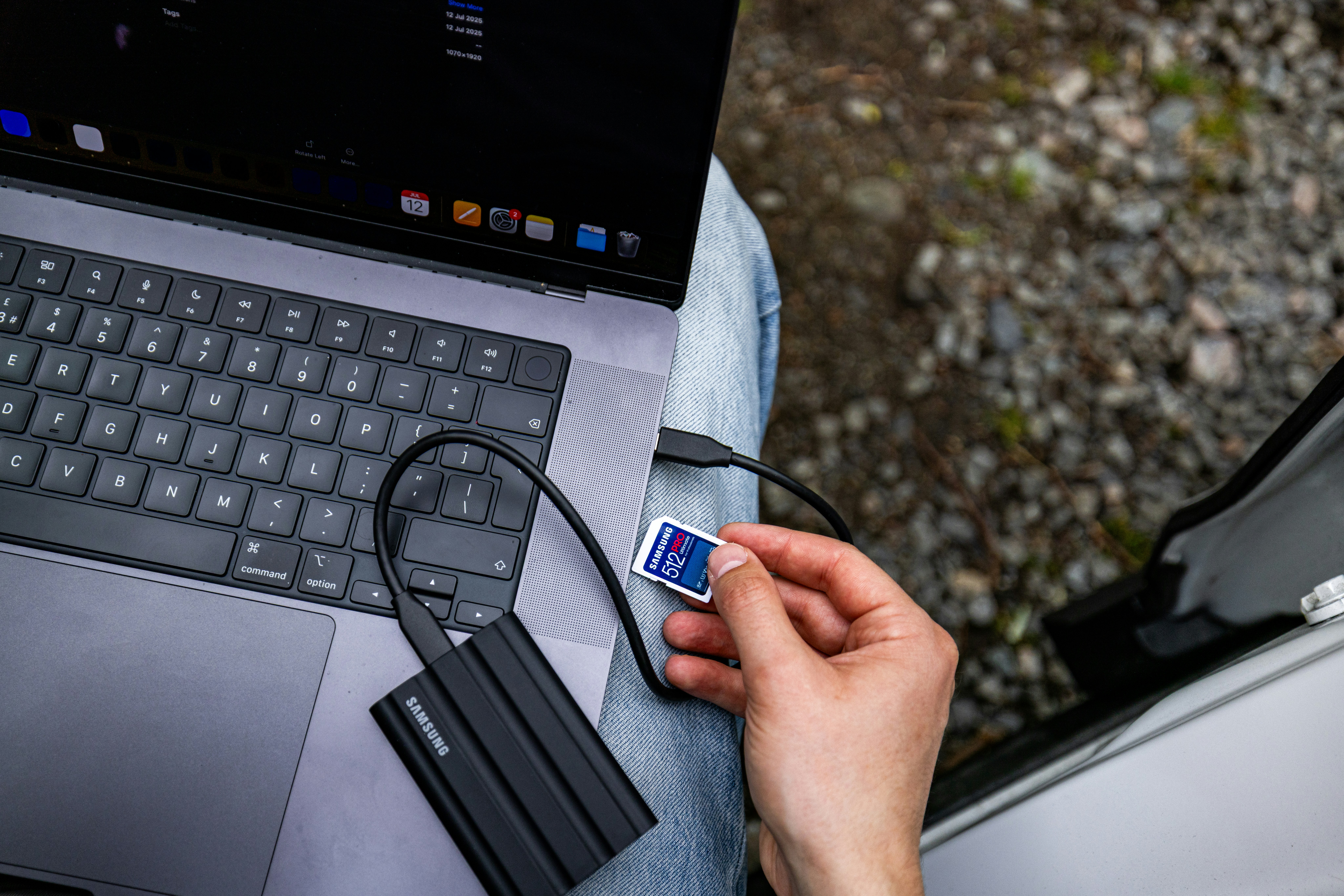 Person inserting sd card into external hard drive connected to laptop