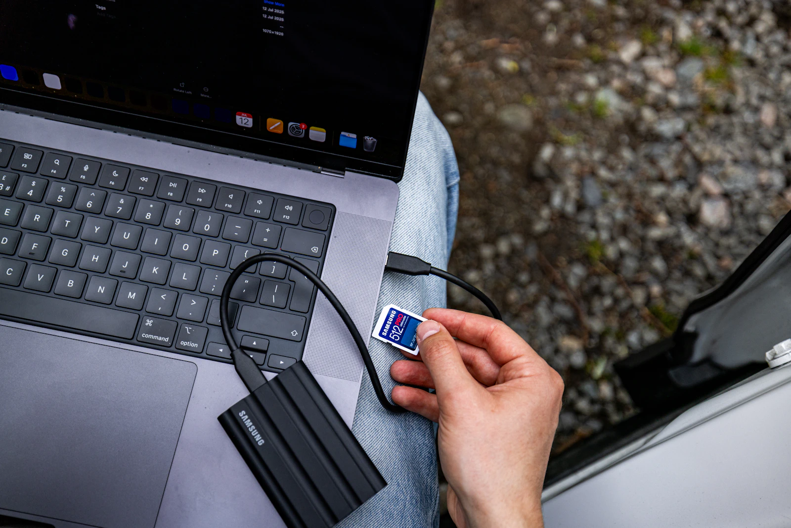 Person connecting a memory card to an external drive attached to a laptop
