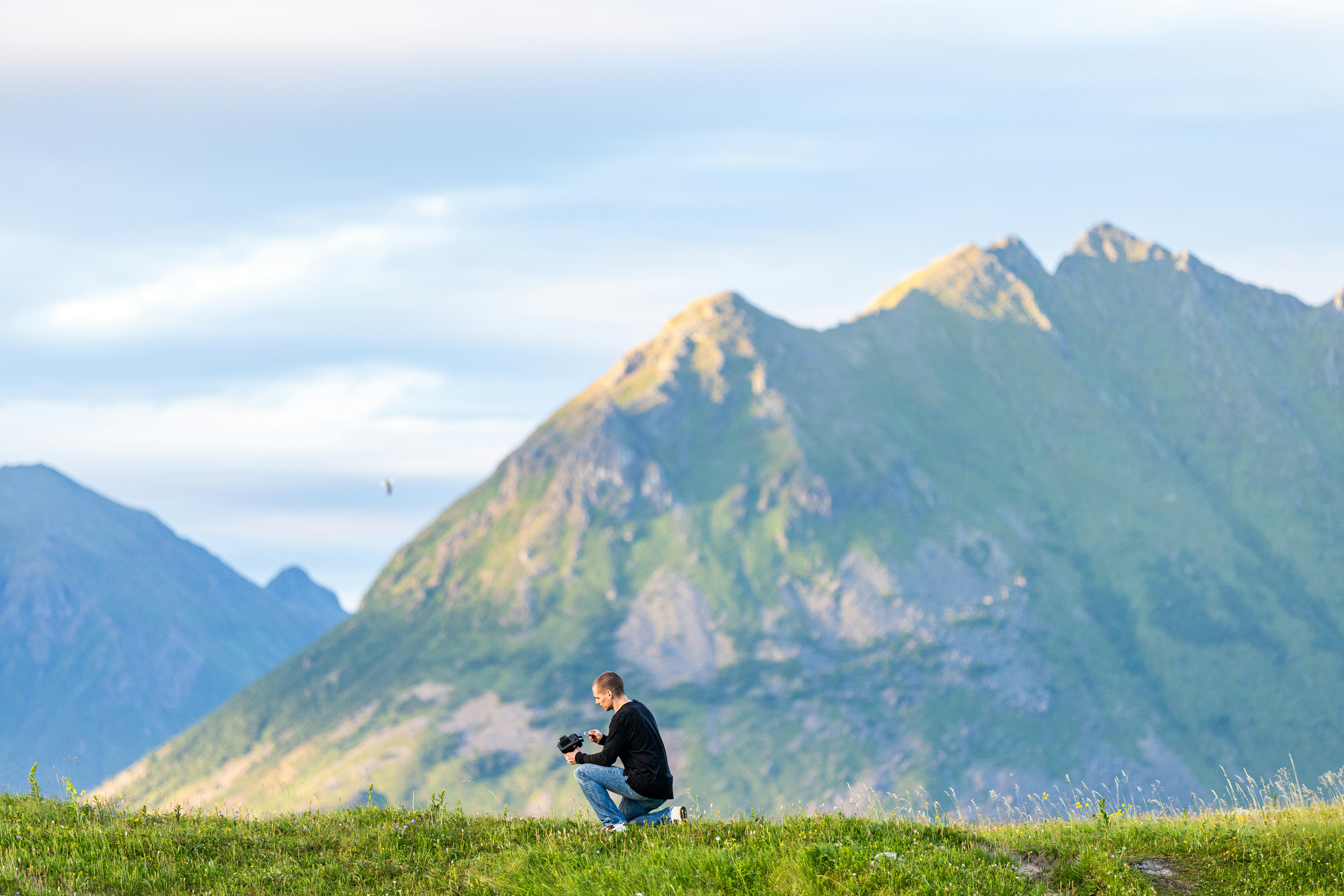 Man crouching with mountains in background