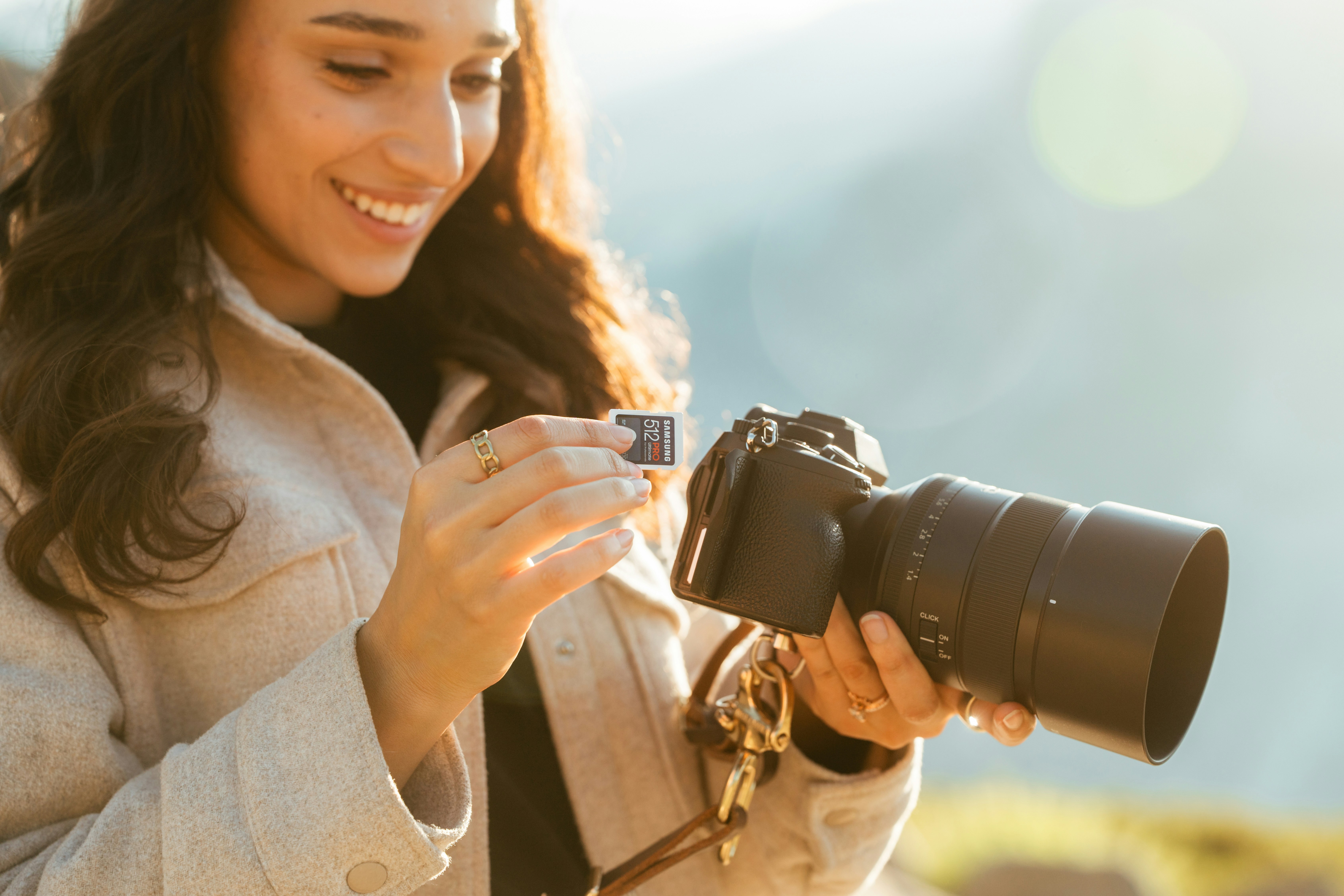Woman holding camera and memory card outdoors