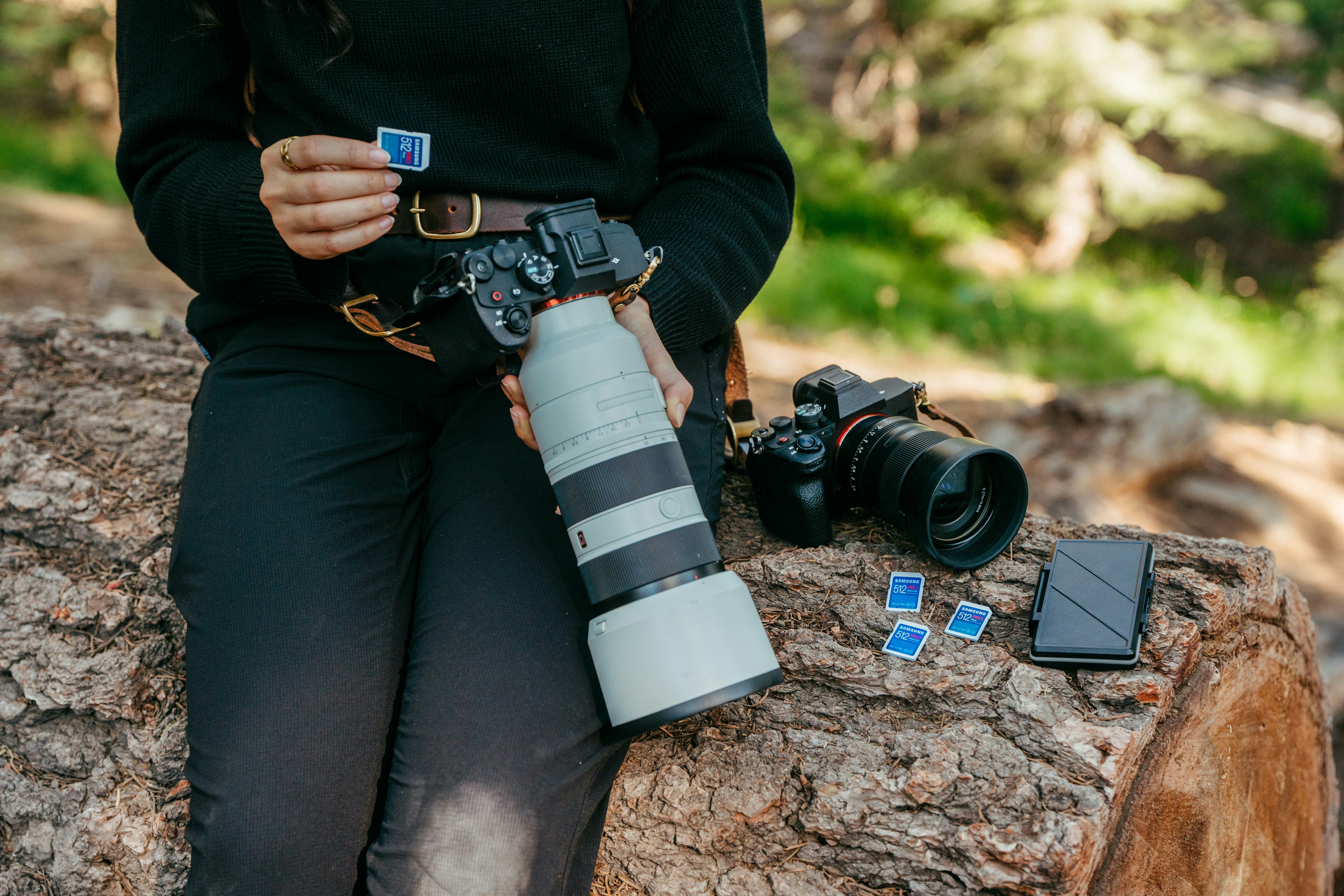Photographer with camera and lenses on log