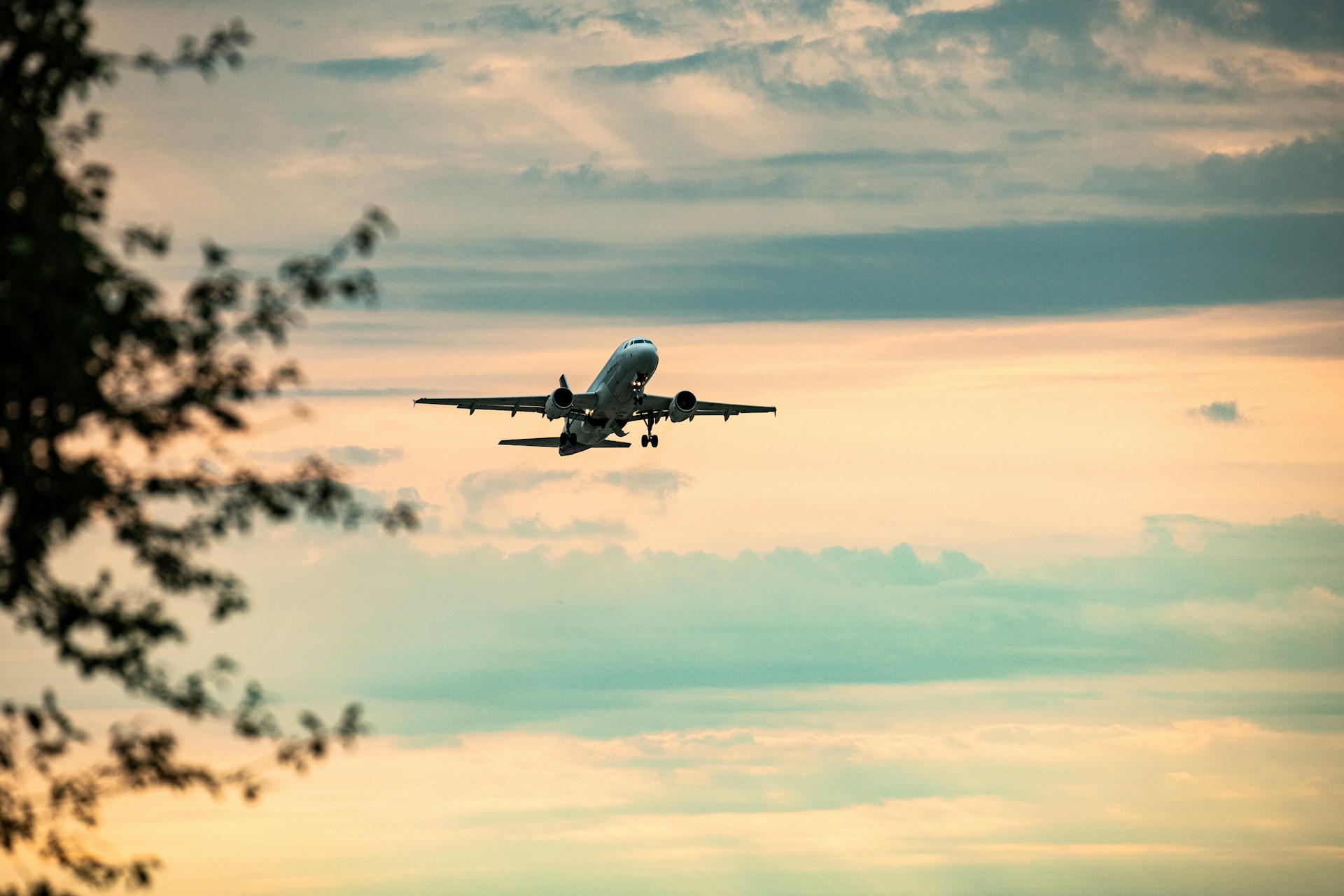 Airplane ascending against a cloudy sky at sunset.