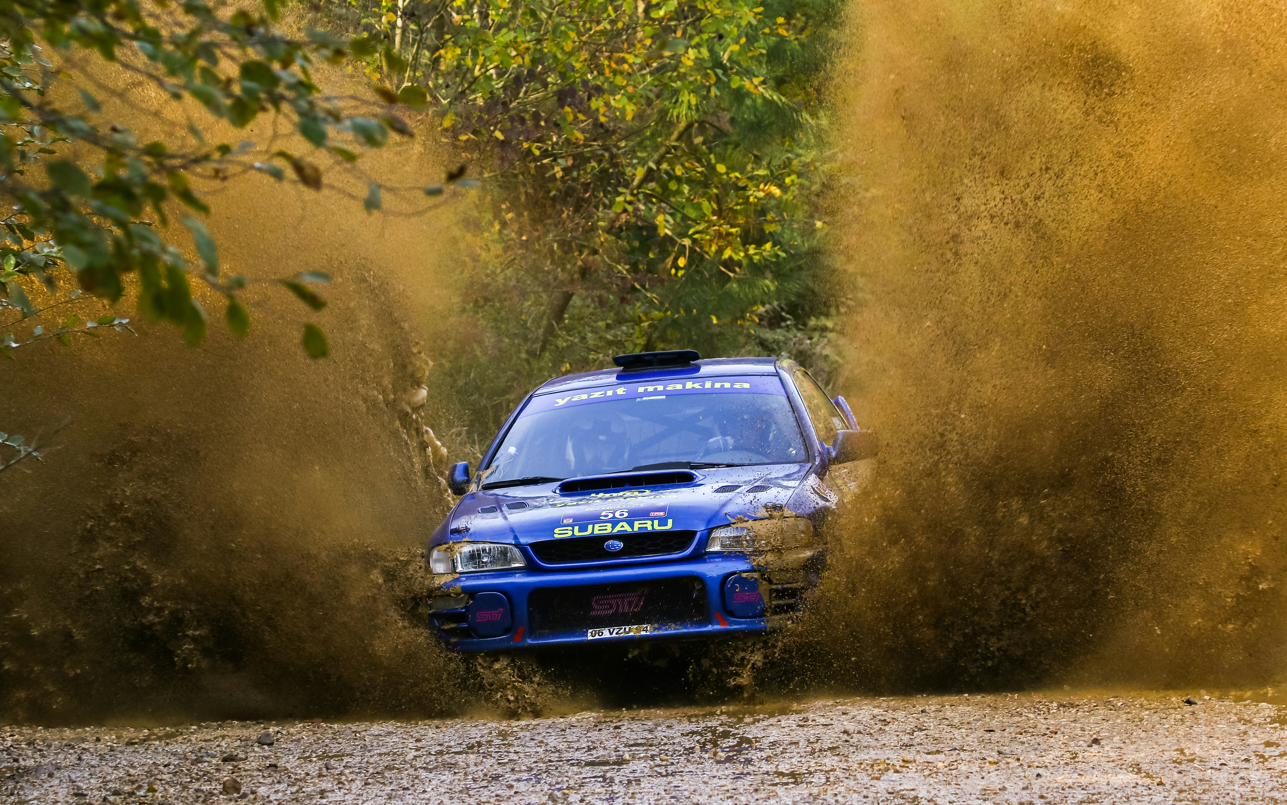 Blue rally car driving through muddy water