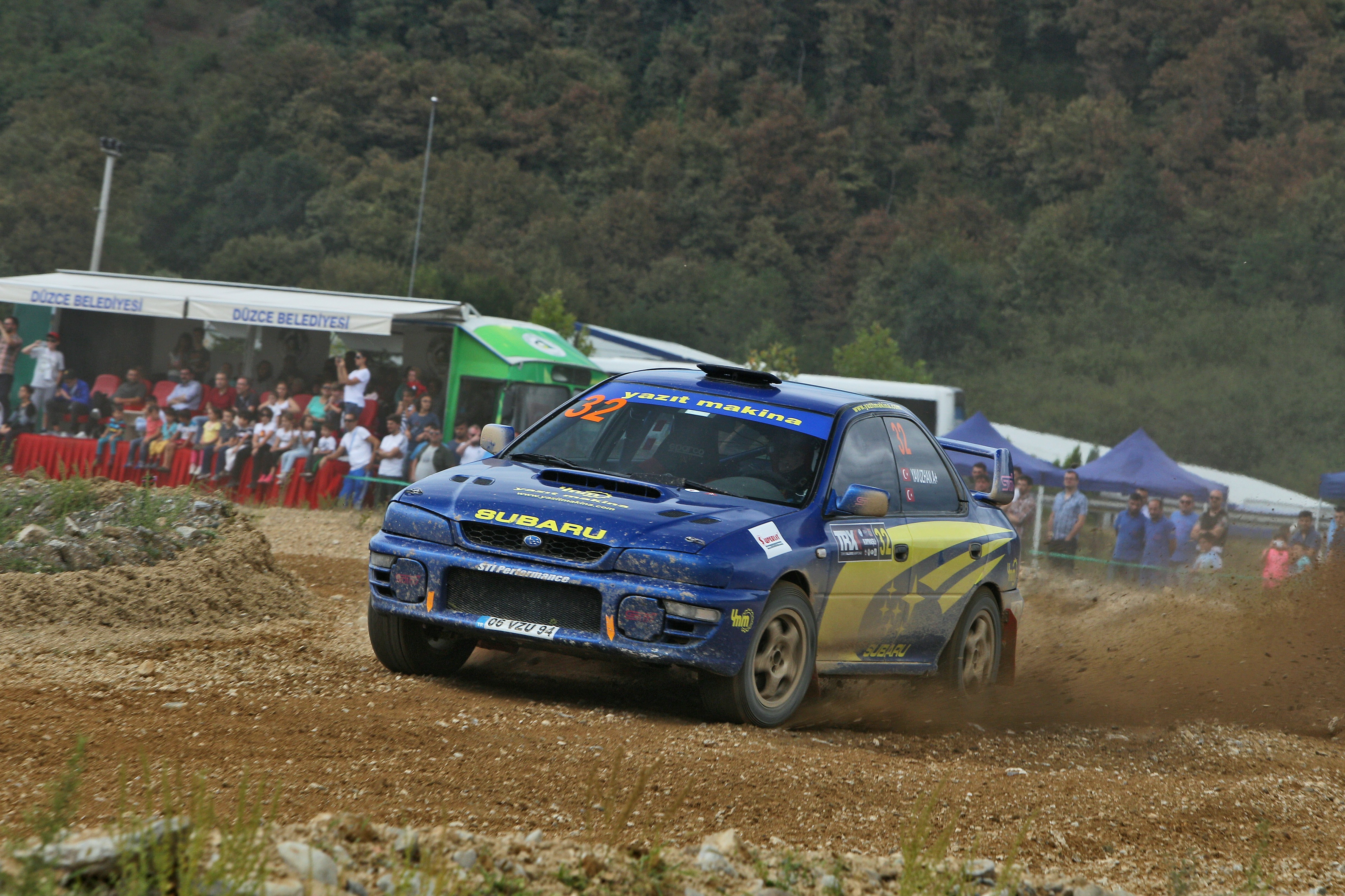 Blue subaru rally car kicking up dirt at race.