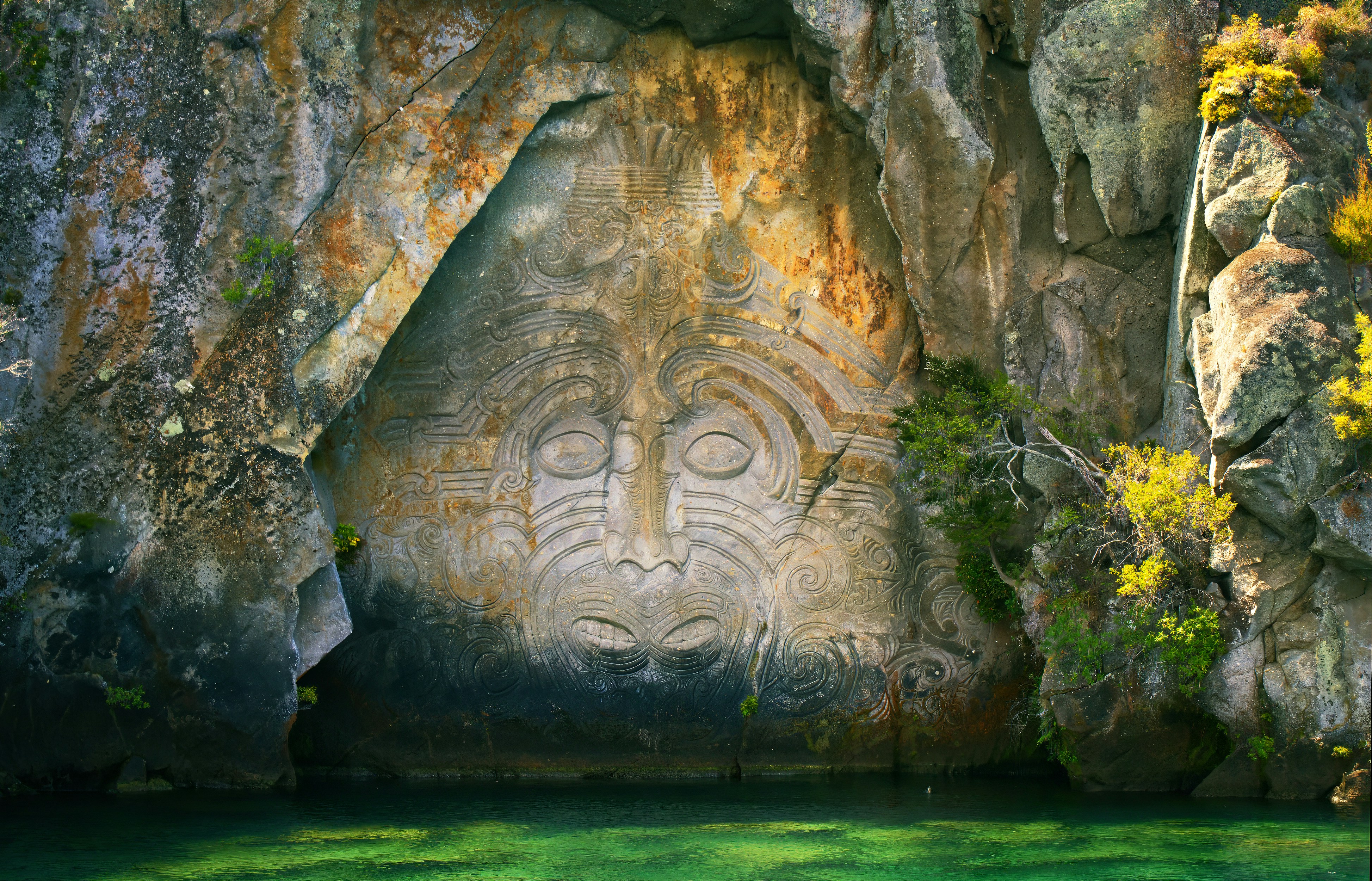 Maori carving on a cliff face above water