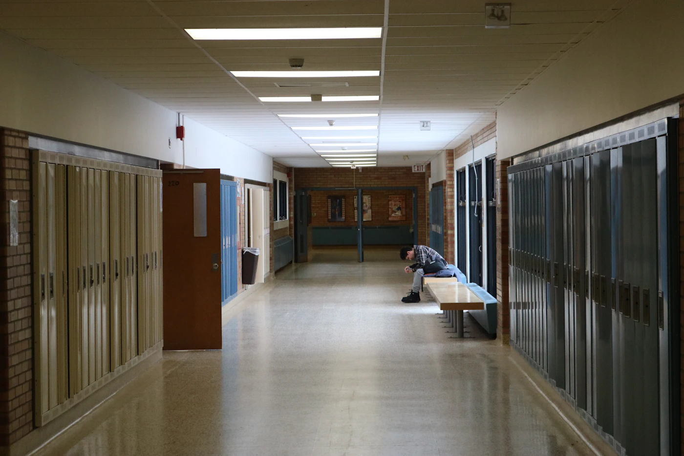 A student sitting alone in a school hallway