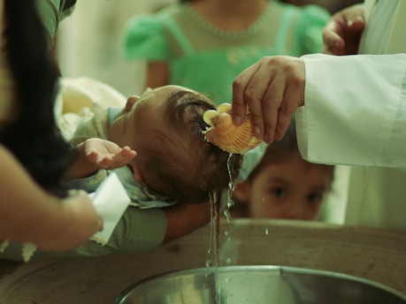 Baby being baptized with water poured on head