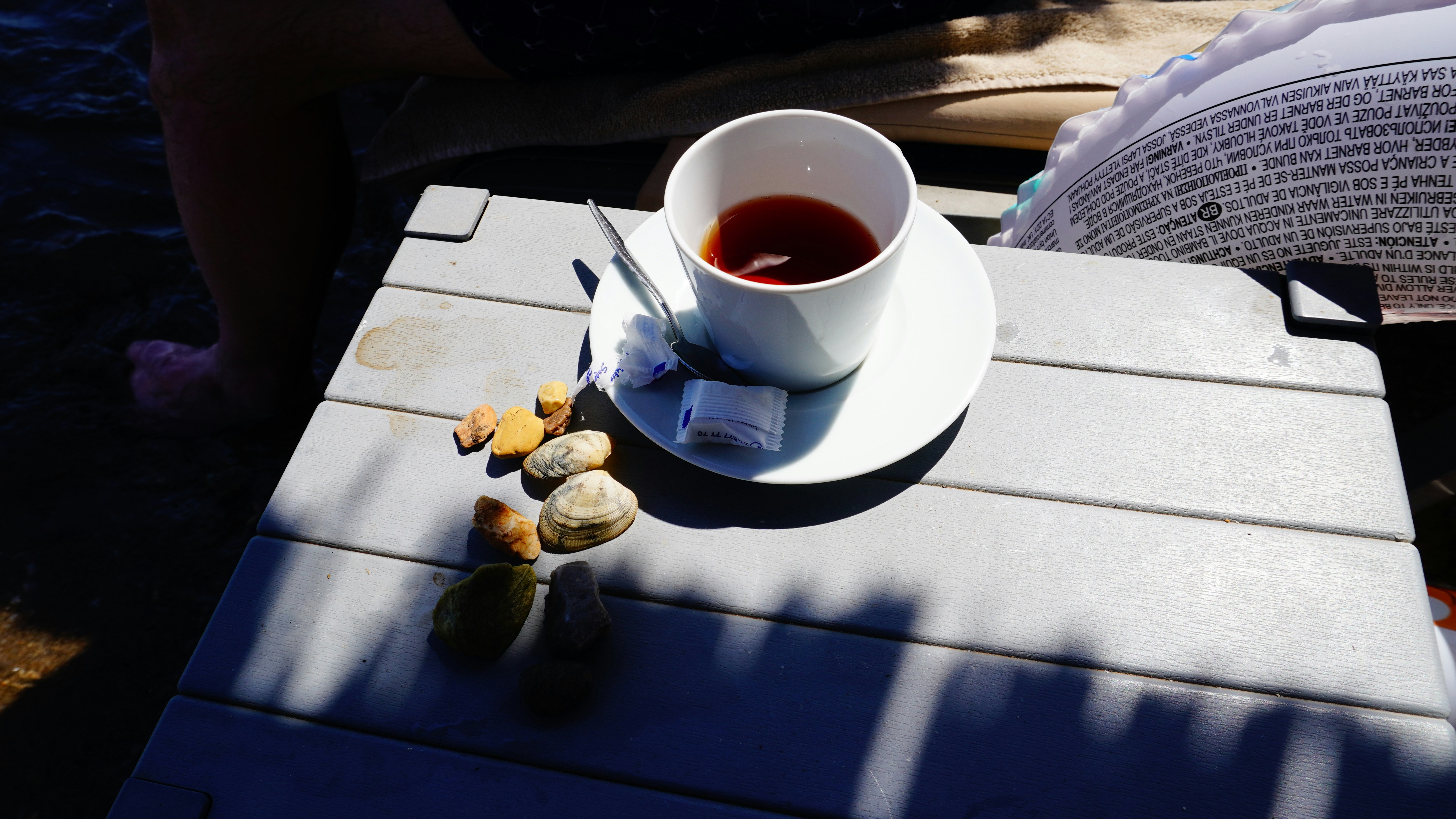 Cup of tea with sugar cubes and stones on table