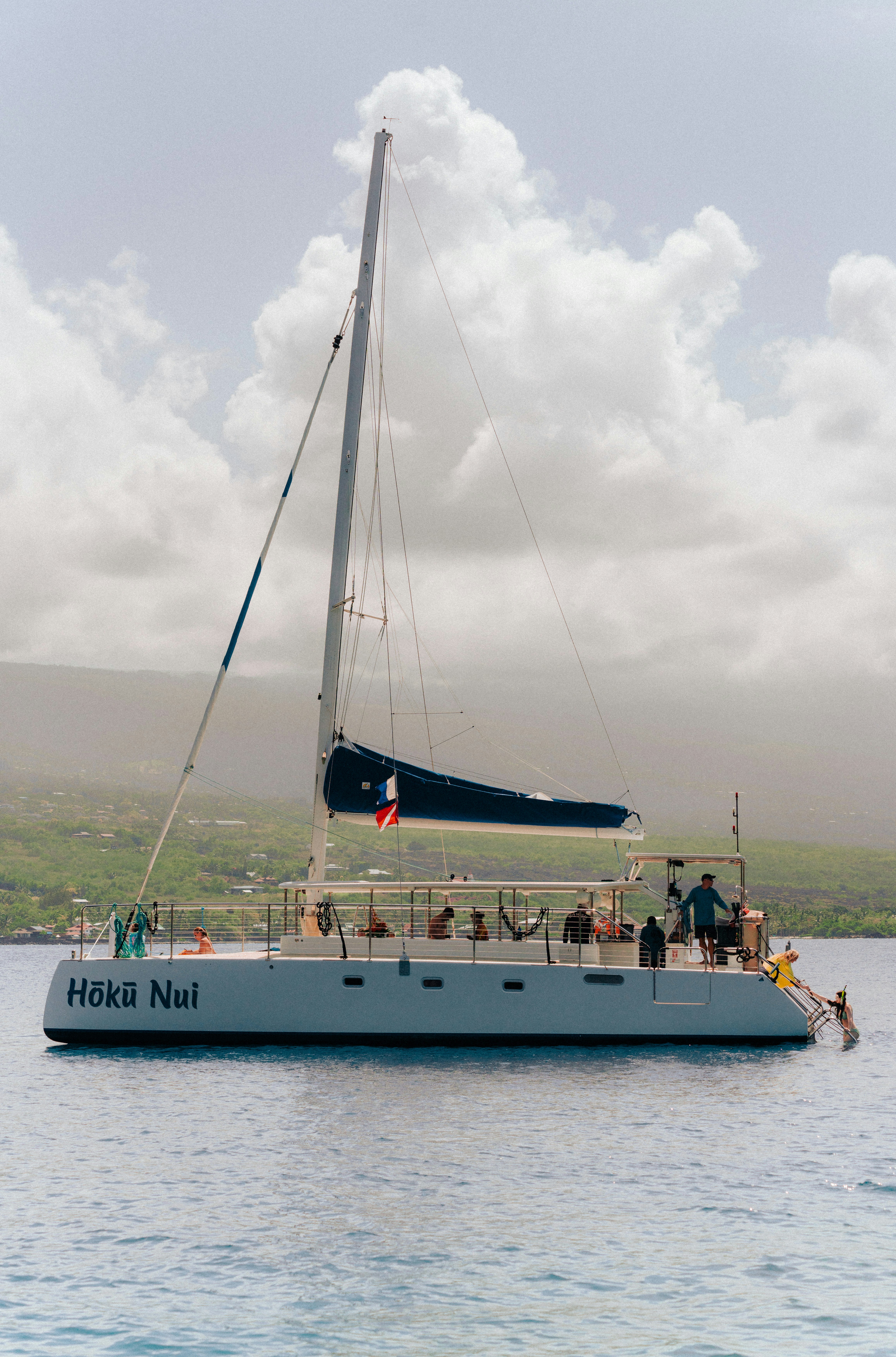 Catamaran sailboat with people on deck in the ocean