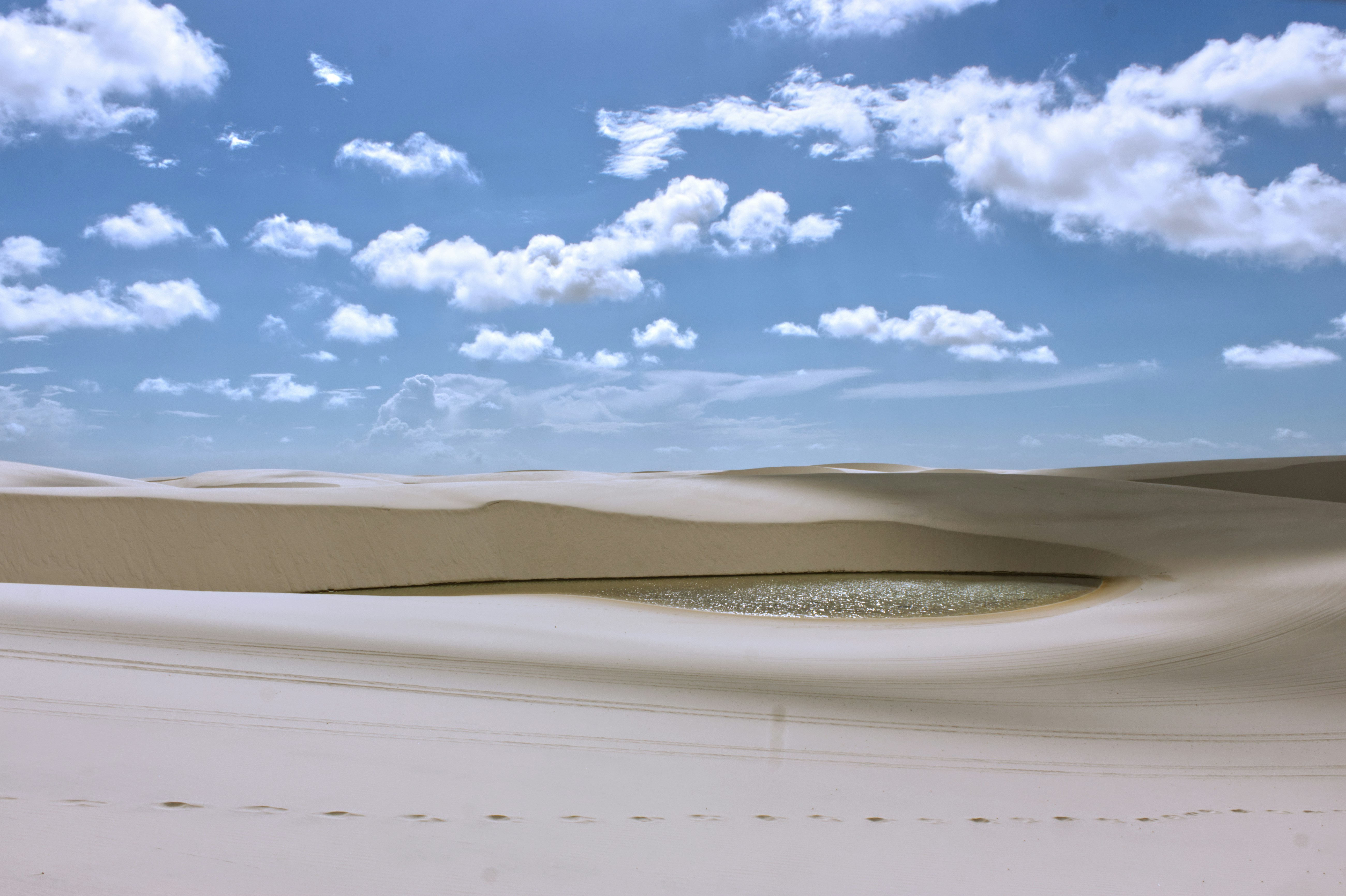 Sanddünen mit einer kleinen Lagune unter blauem Himmel.