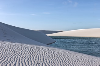 White sand dunes with rippled texture and blue water.