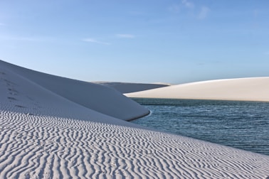 White sand dunes with rippled texture and blue water.