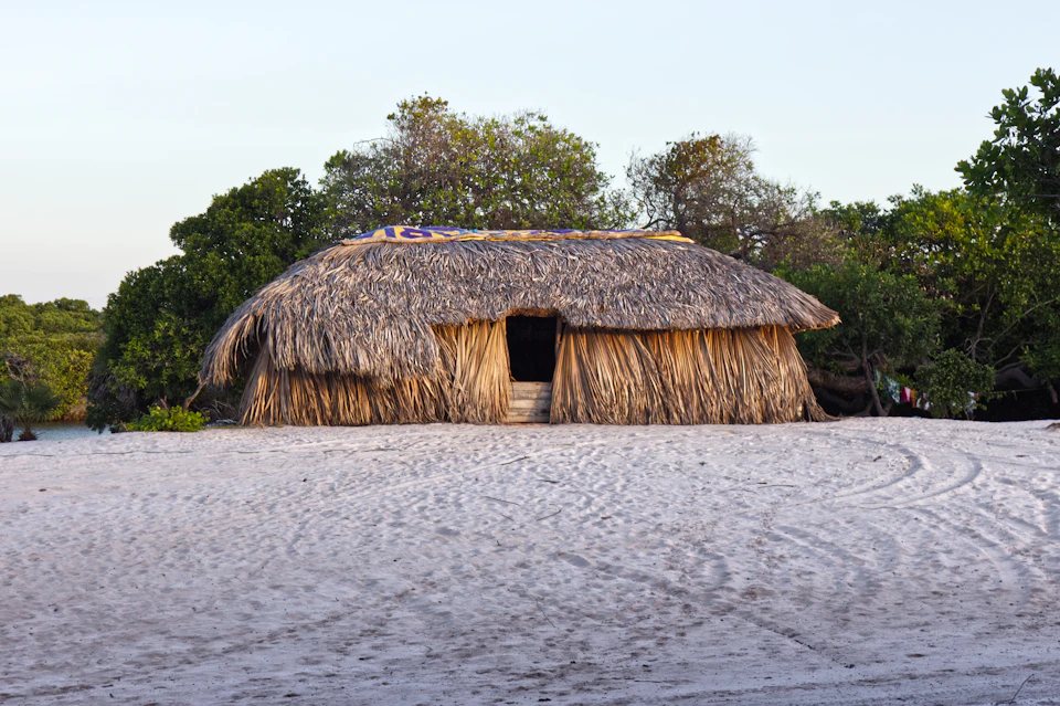 Thatched roof hut on sandy beach with open entrance and sloping straw roof structure