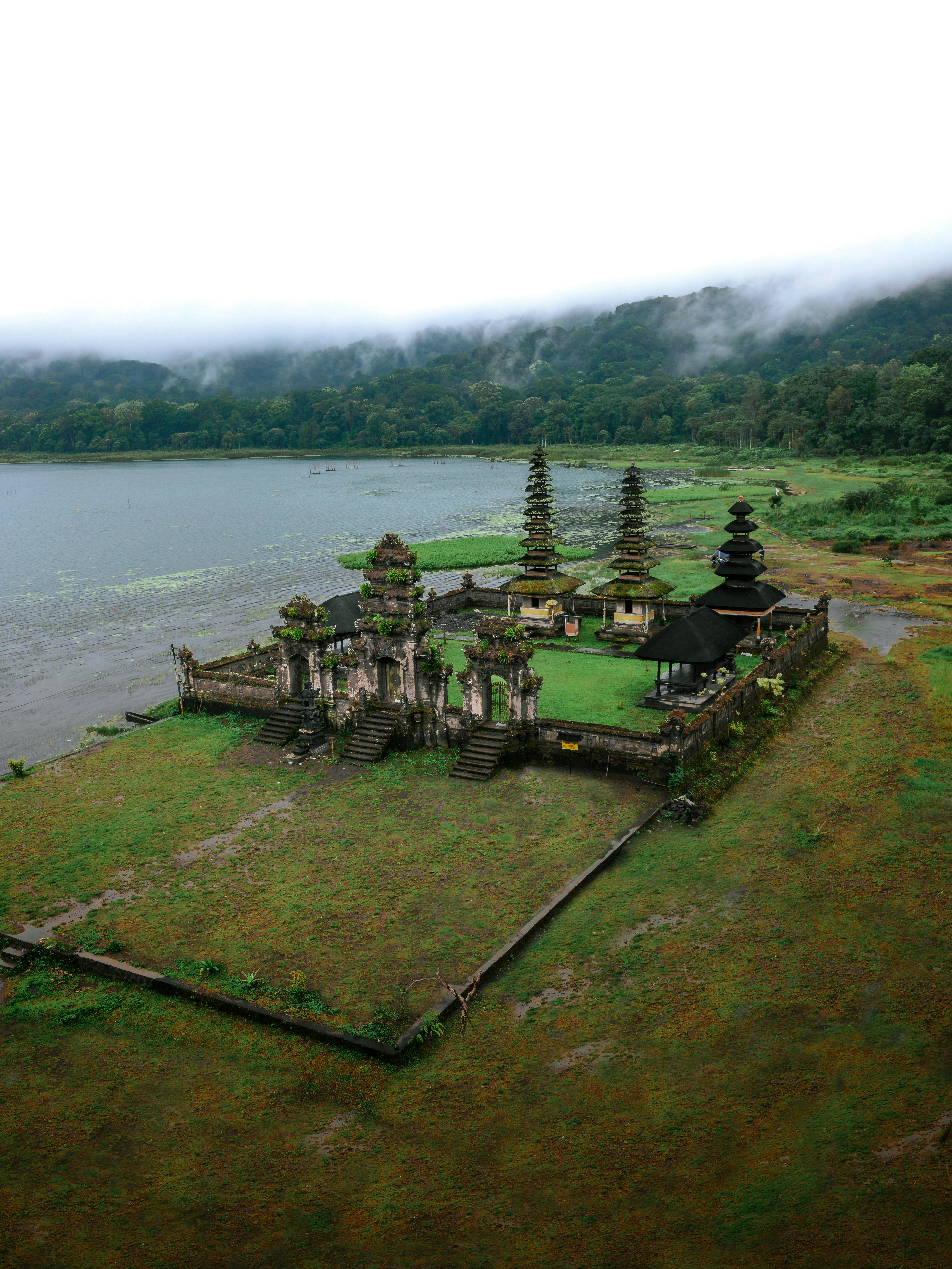 Ancient temple complex on a grassy shore by a lake.
