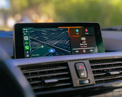 Car dashboard displaying navigation and music apps.