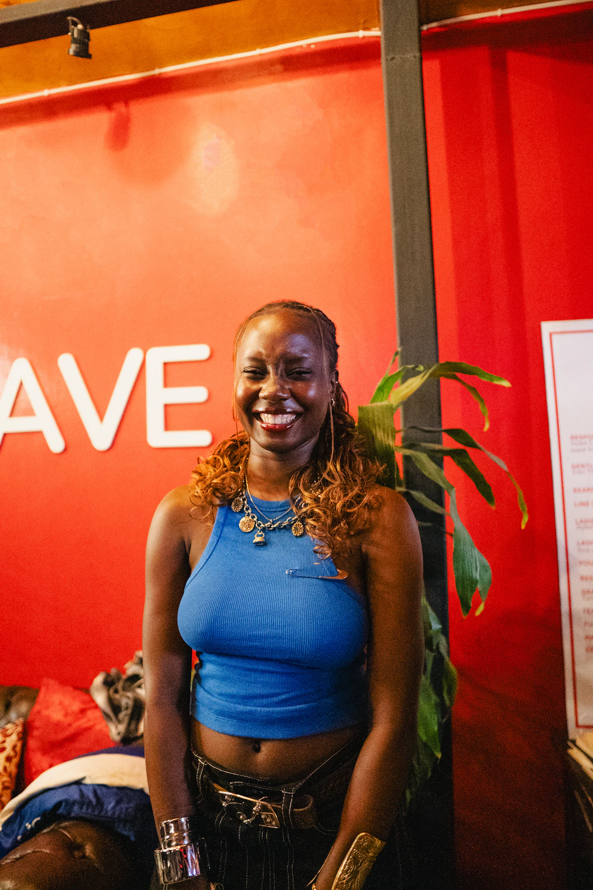 Young woman with braids smiling in front of red wall