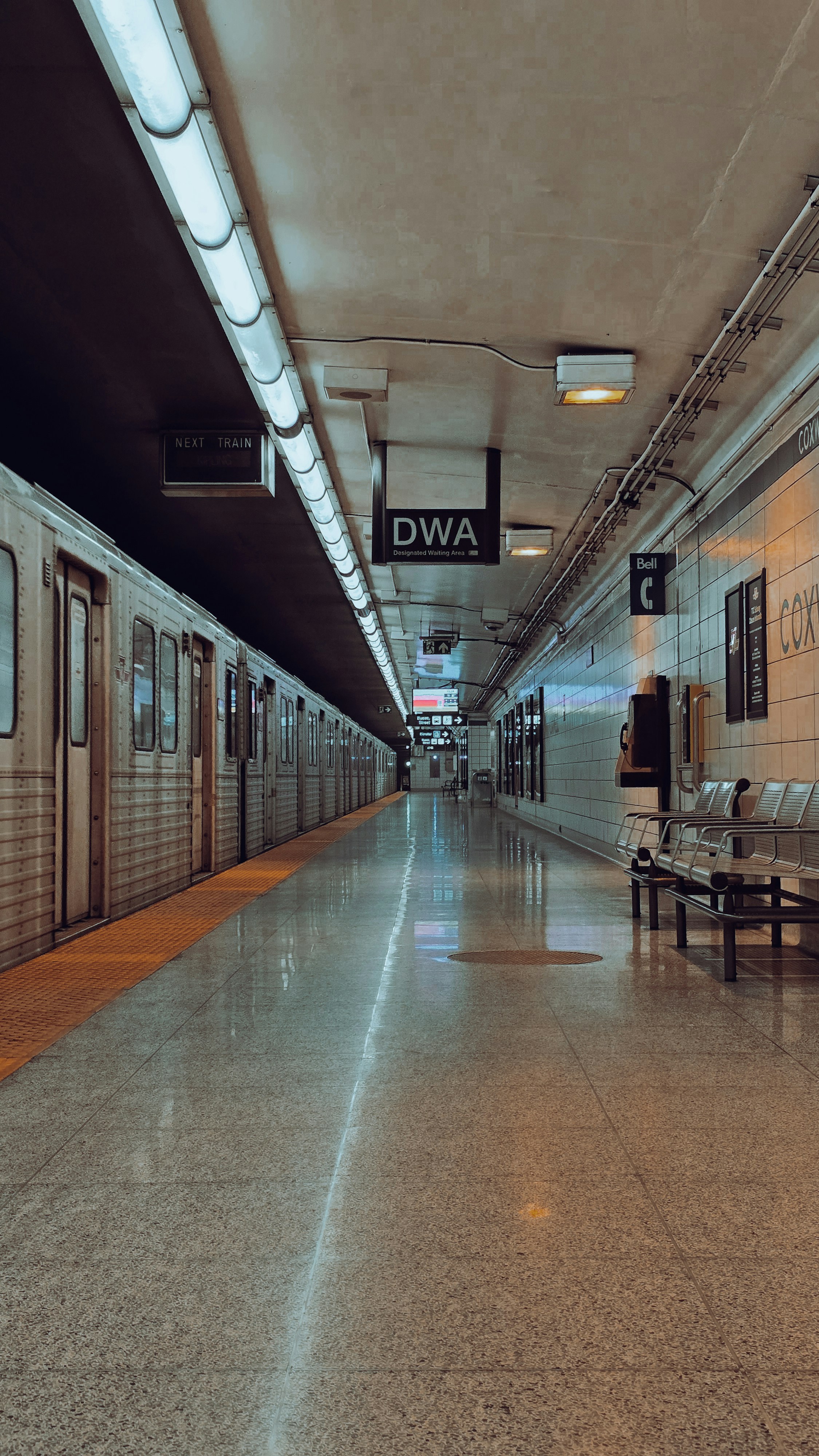 Empty subway platform with train and benches.