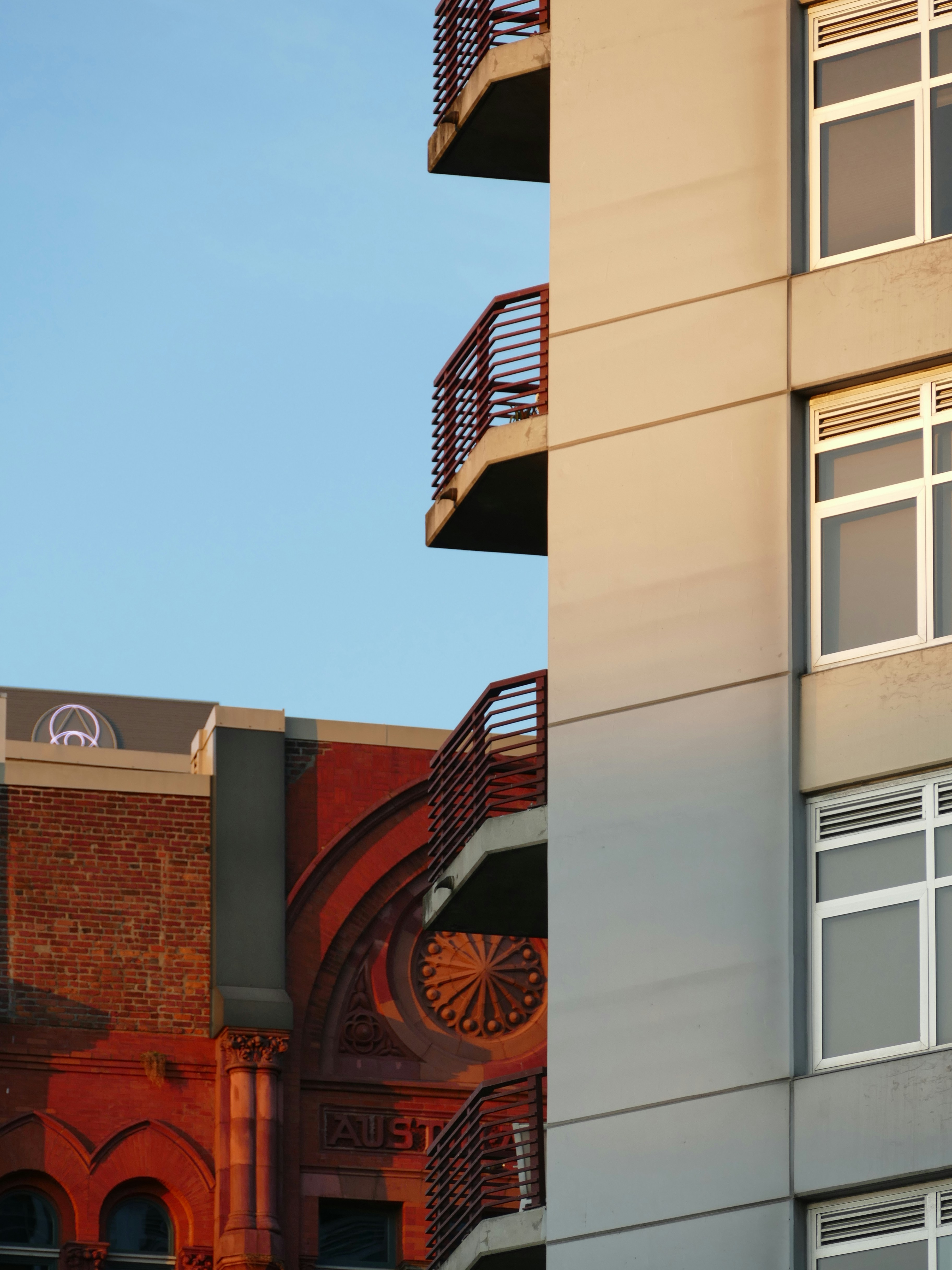 Modern building facade with balconies and old brick building.