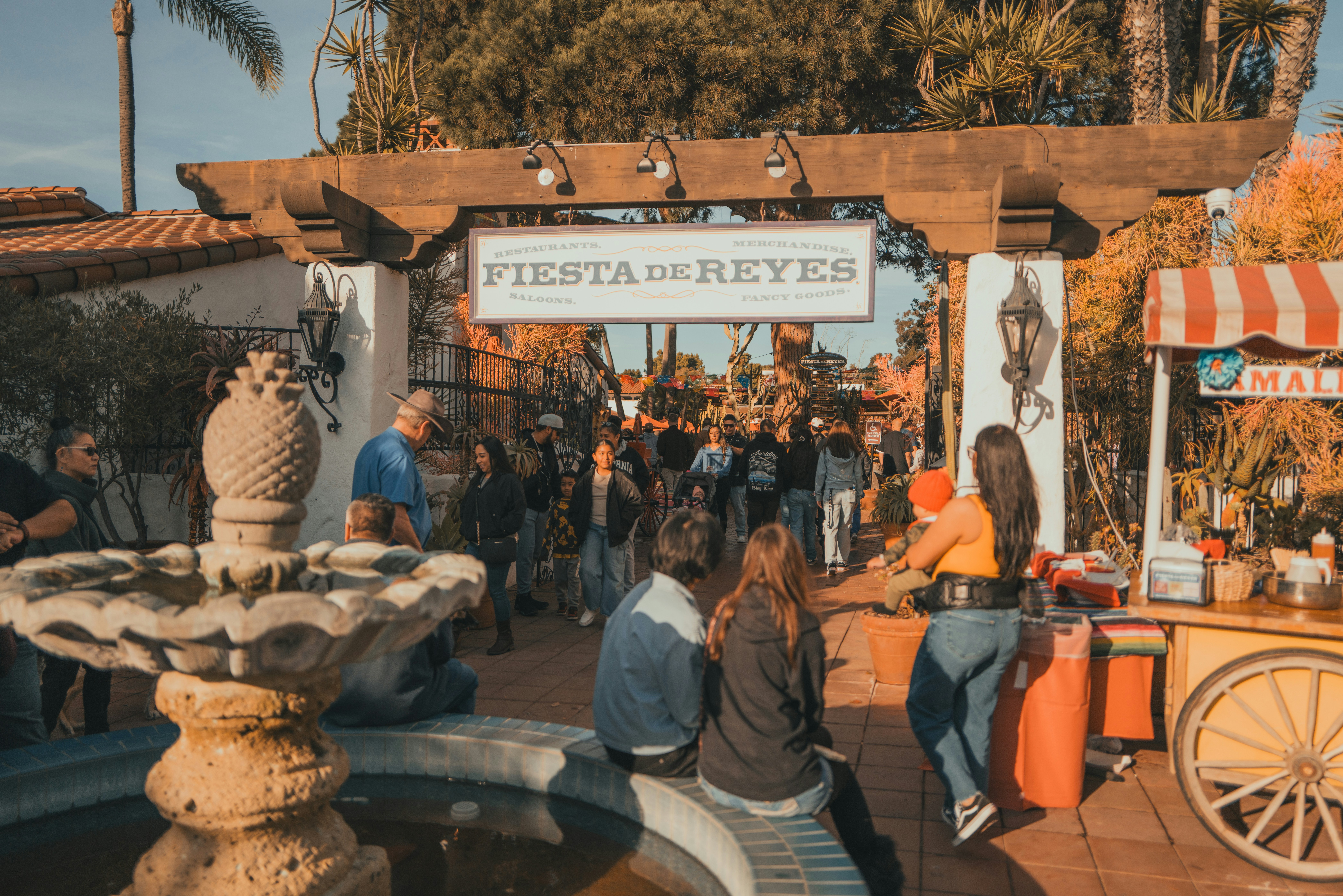 People gather under a wooden archway at an outdoor festival.