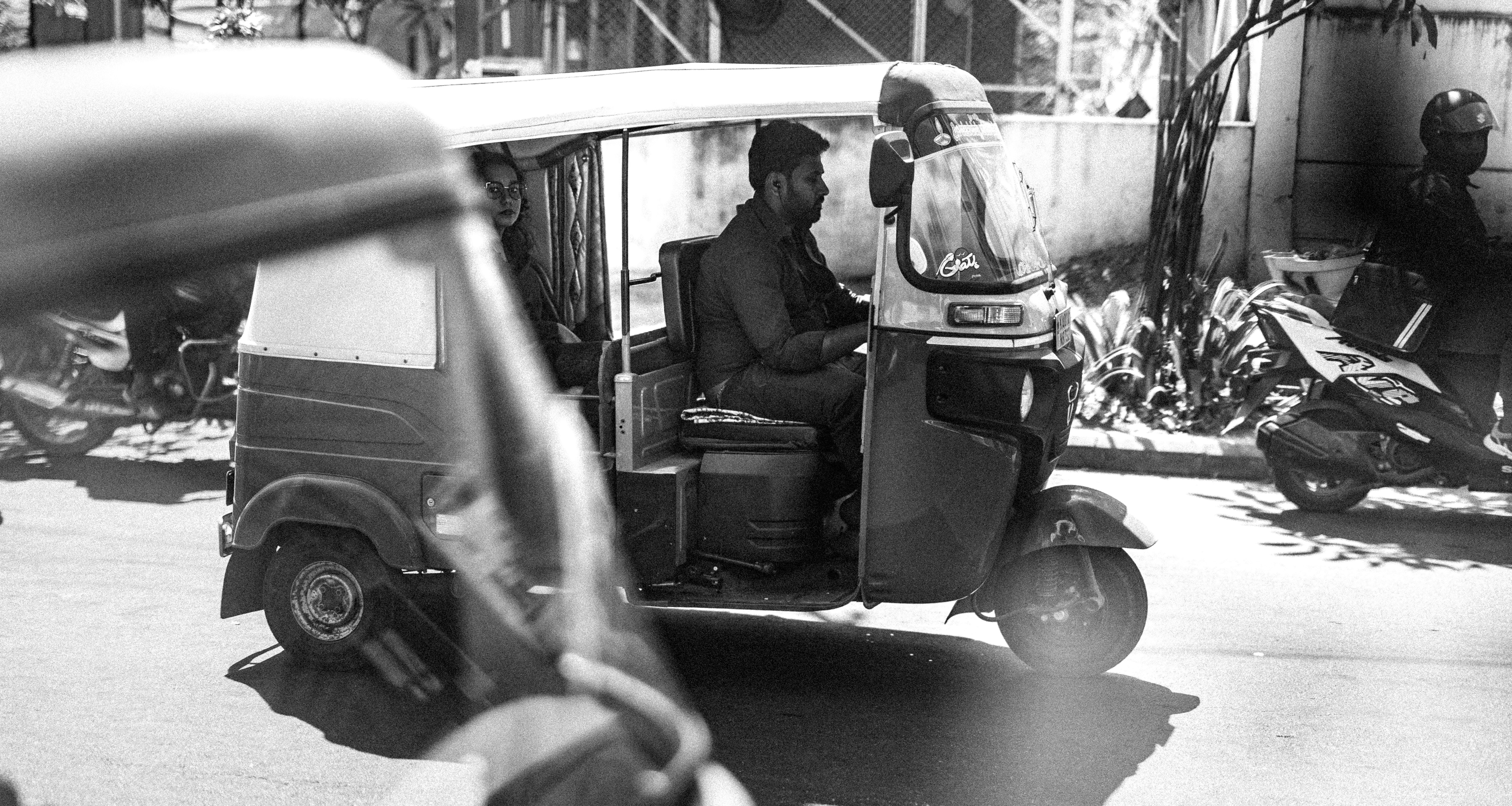 Man driving an auto-rickshaw on a street.