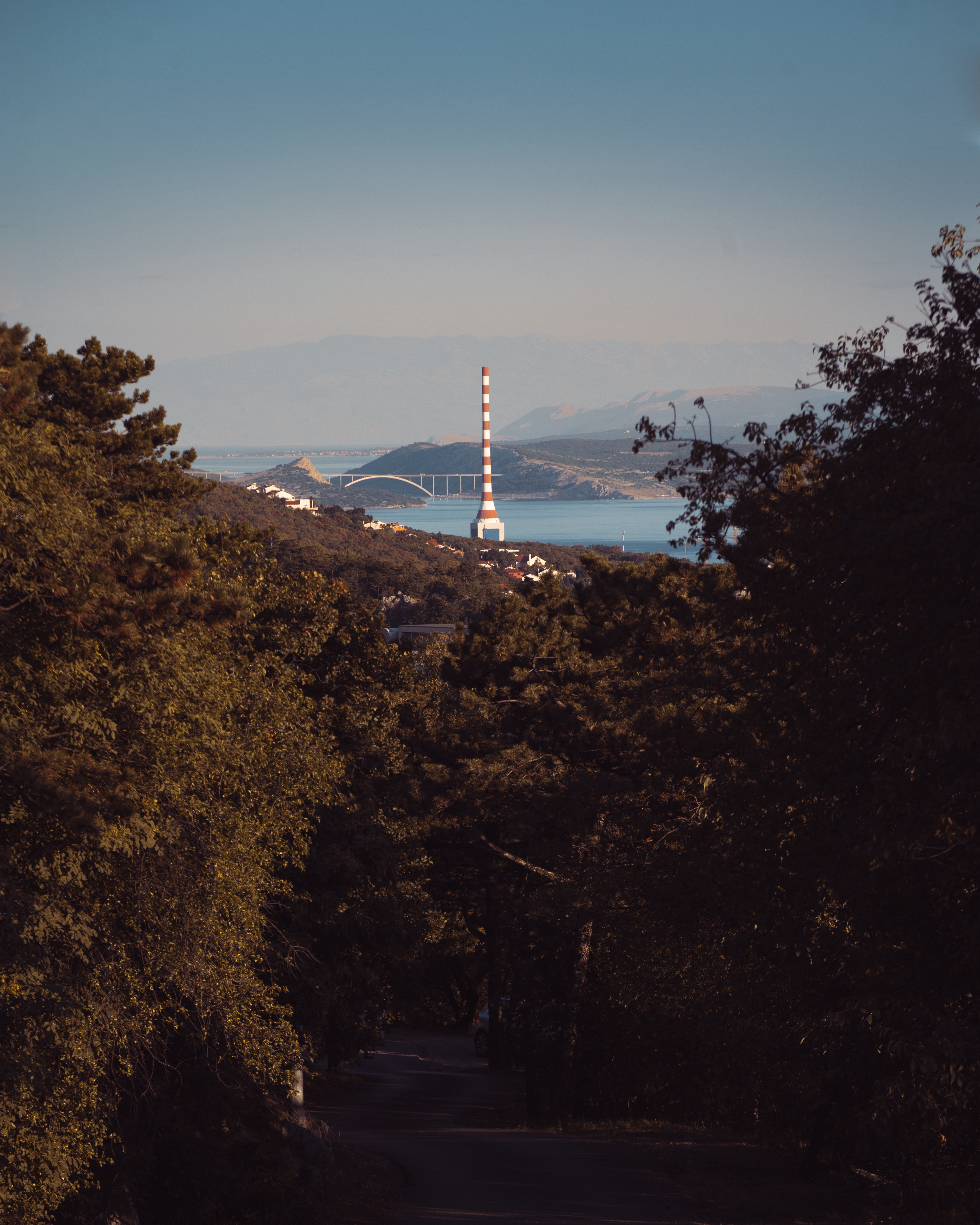 Striped tower near a bridge and body of water.