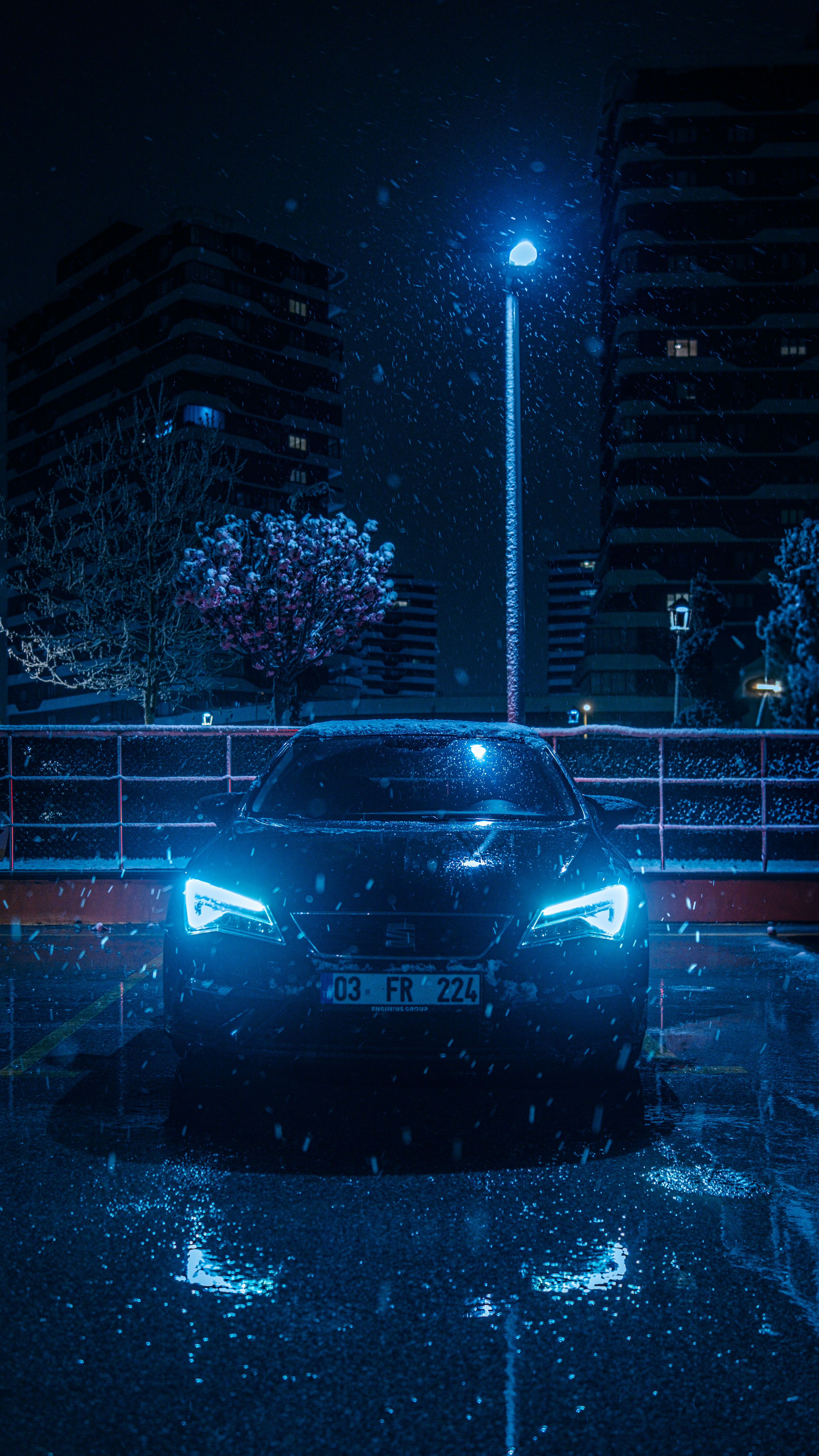 Black car with glowing blue headlights at night
