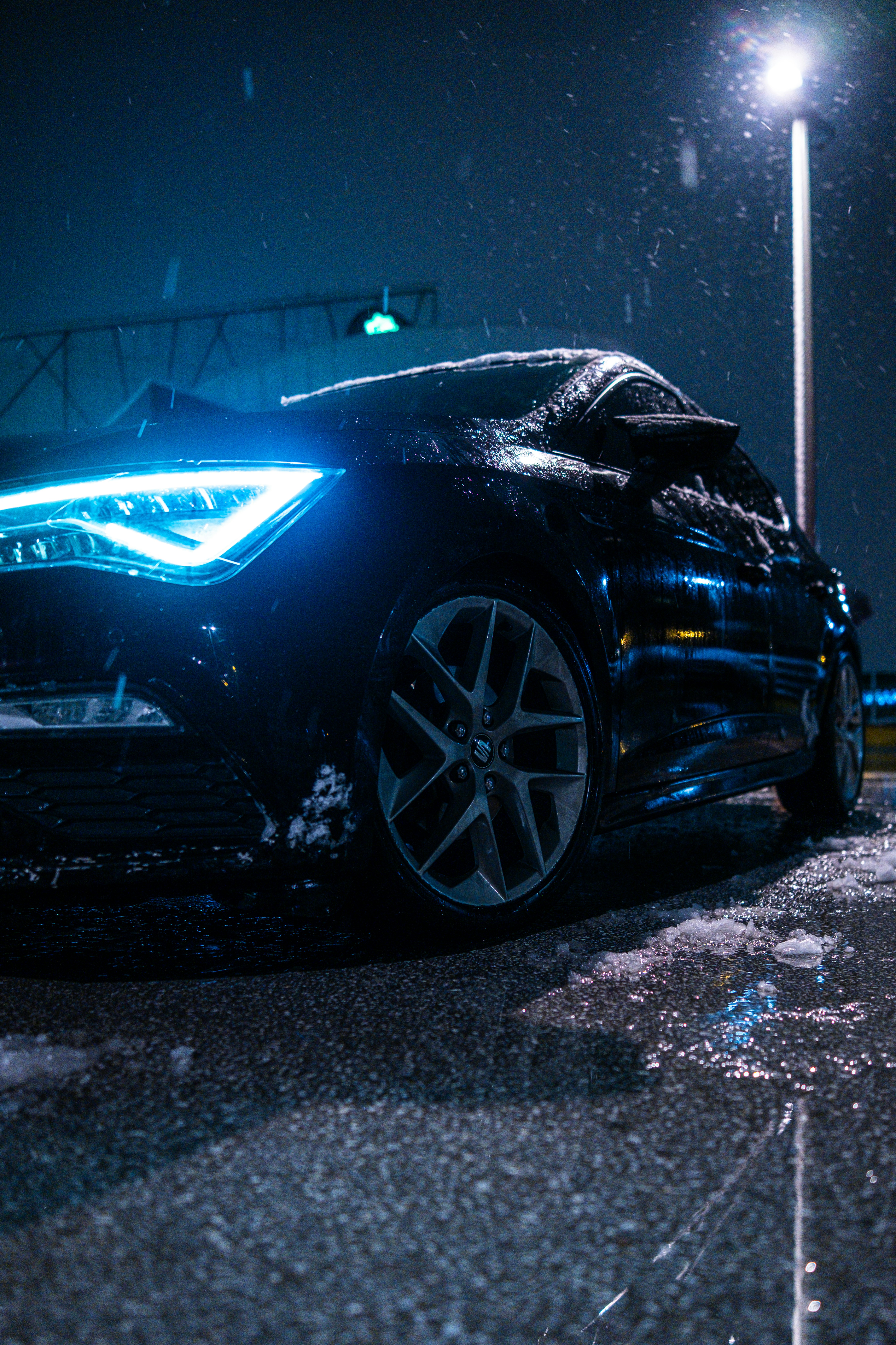 Black car with glowing headlights in the snow