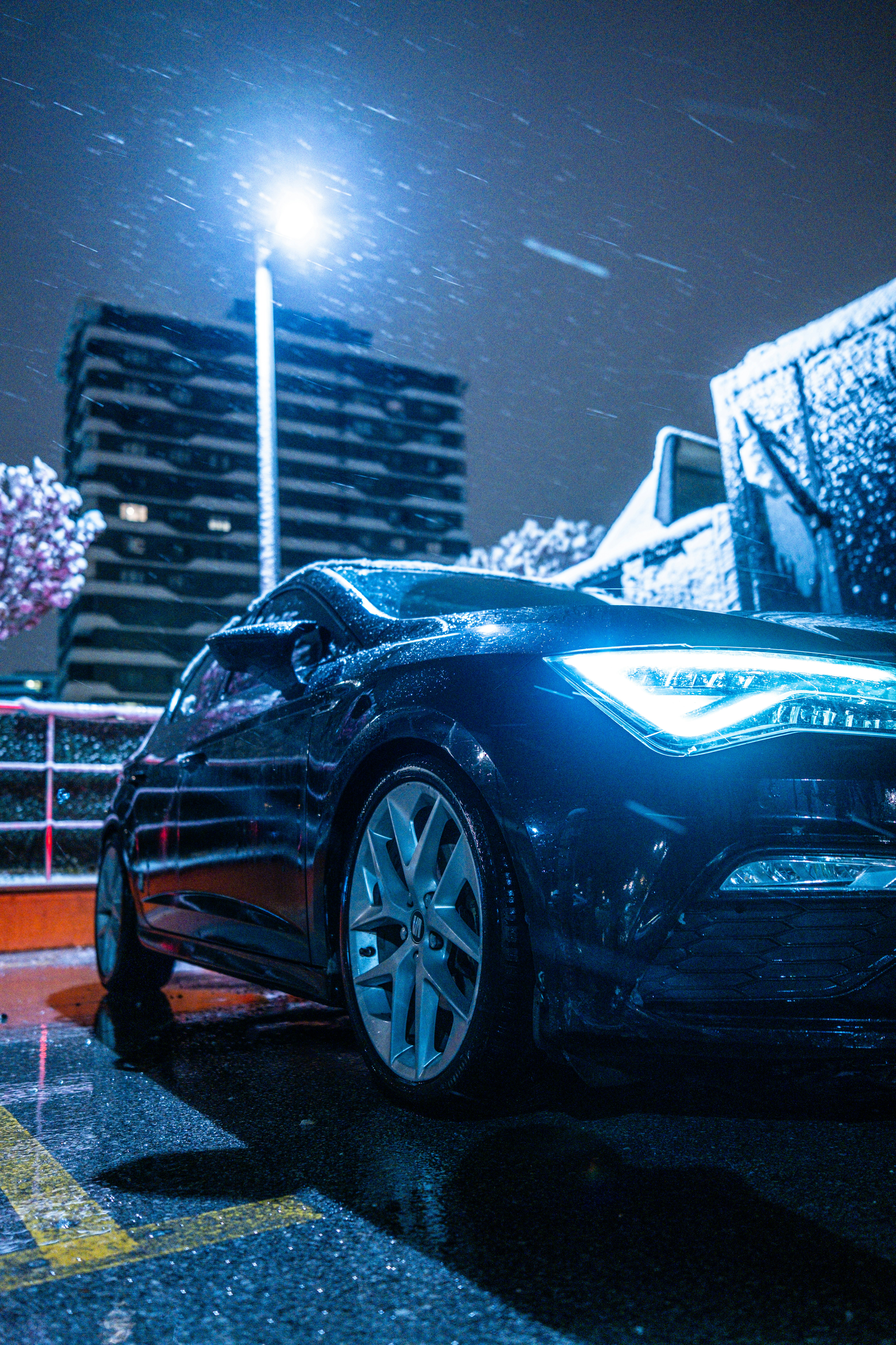 Black car parked on a wet street at night.
