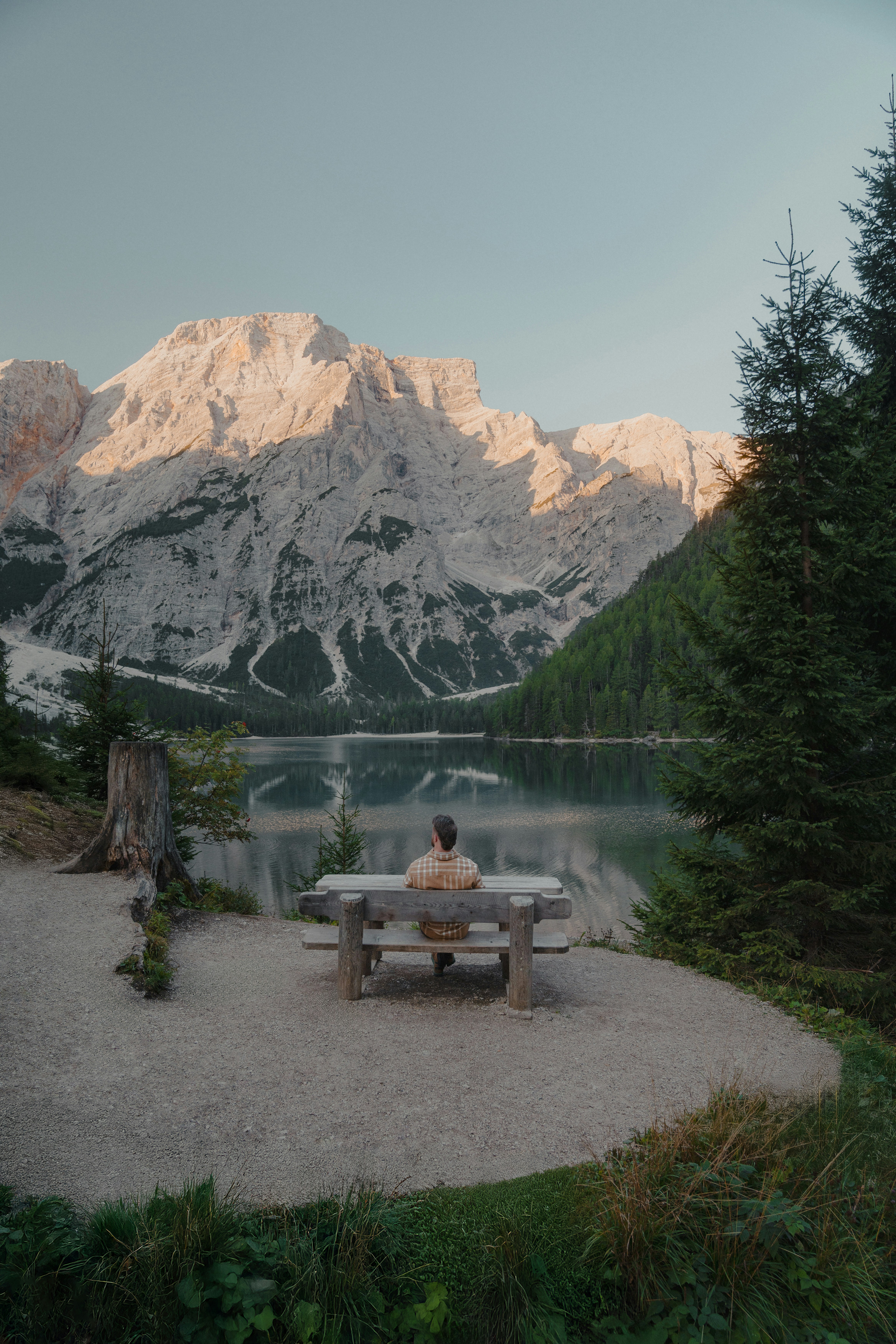 Person sits at picnic table overlooking mountain lake