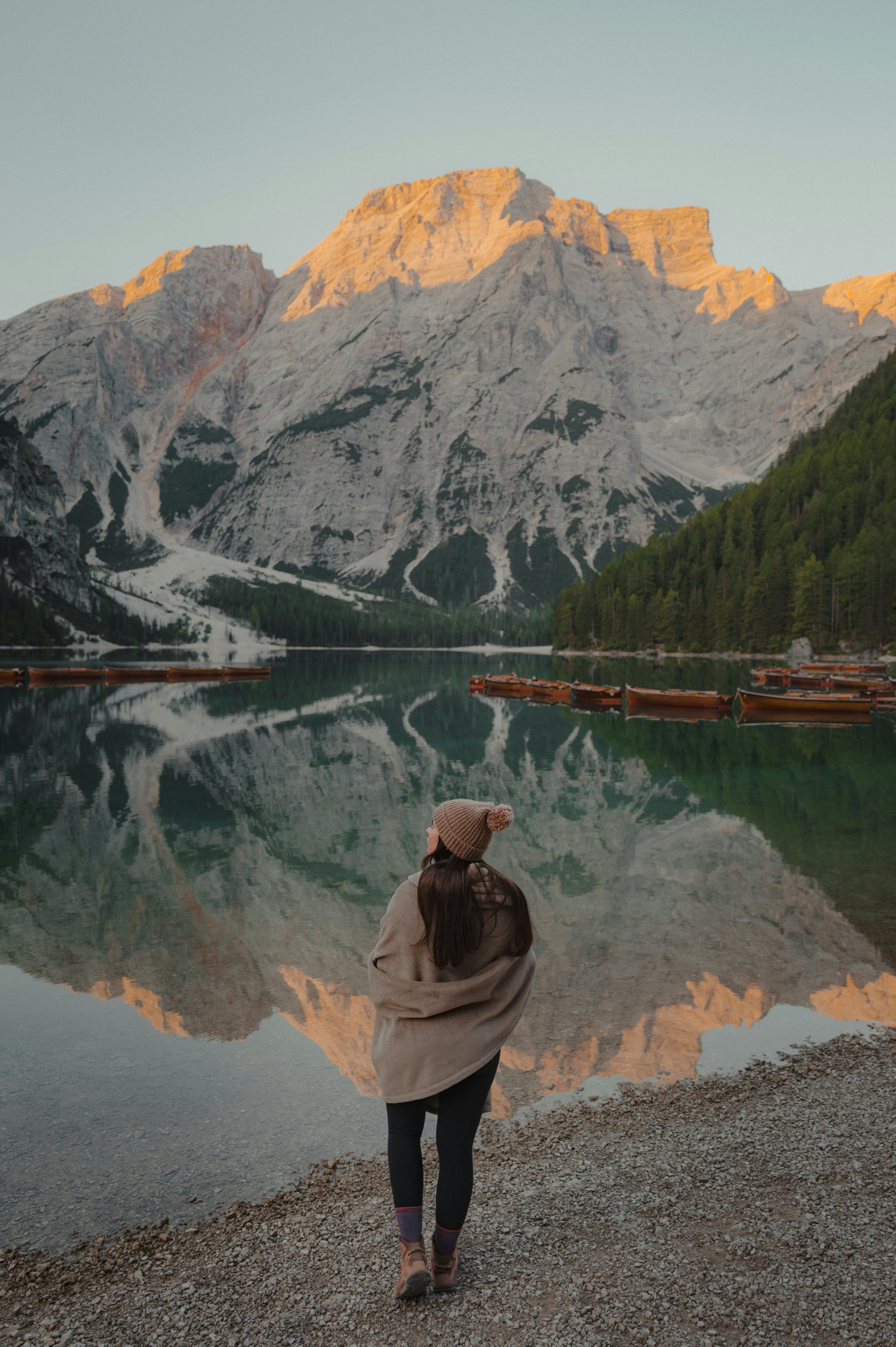 Woman facing a serene mountain lake at sunrise