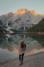 Woman facing a serene mountain lake at sunrise