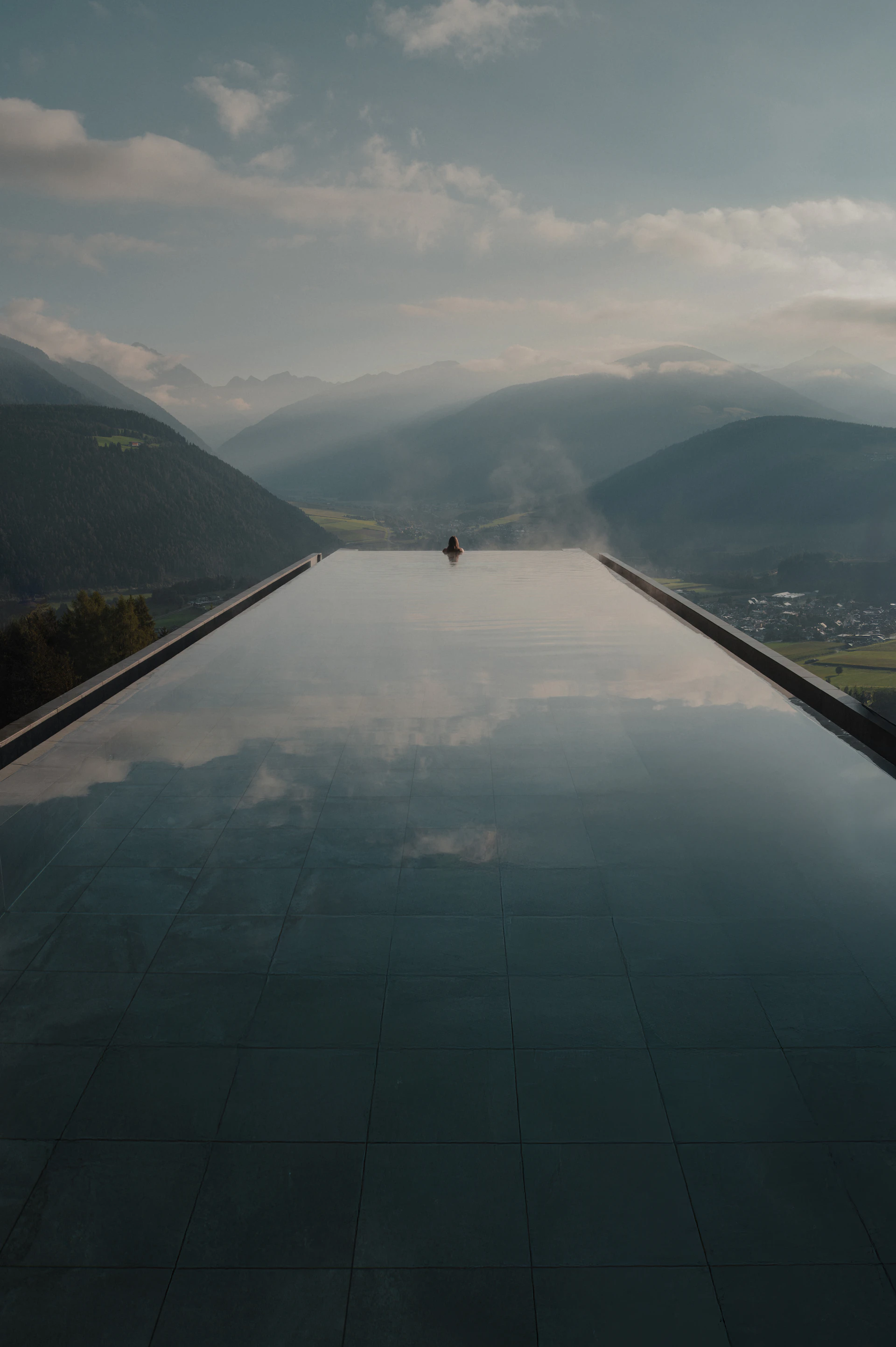 Infinity pool of an alpine wellness hotel overlooking misty mountains in the European Alps