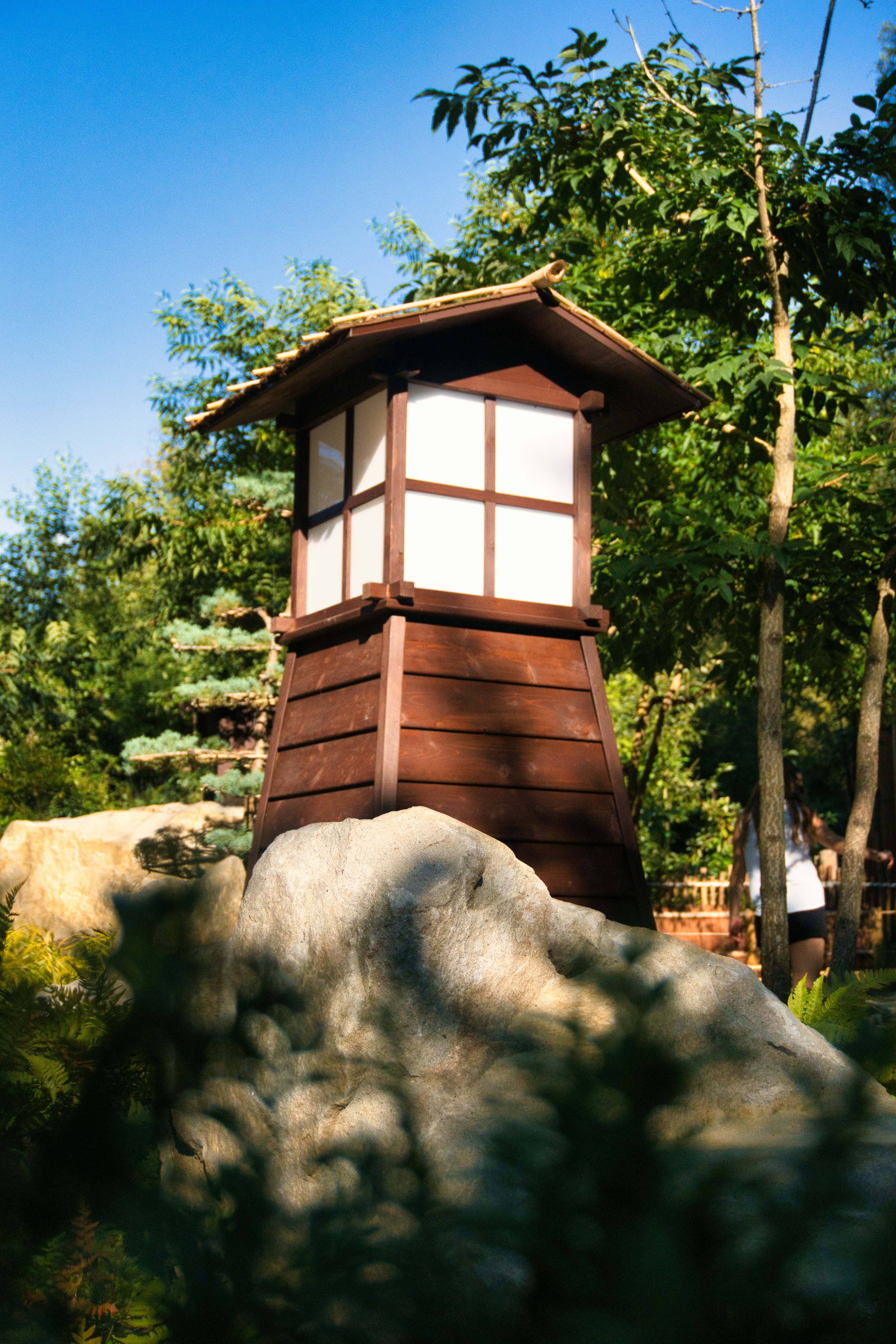 Wooden japanese lantern on a rock in a garden.