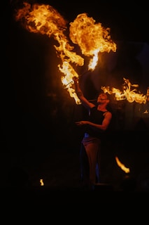 Performer breathes fire against a dark background.