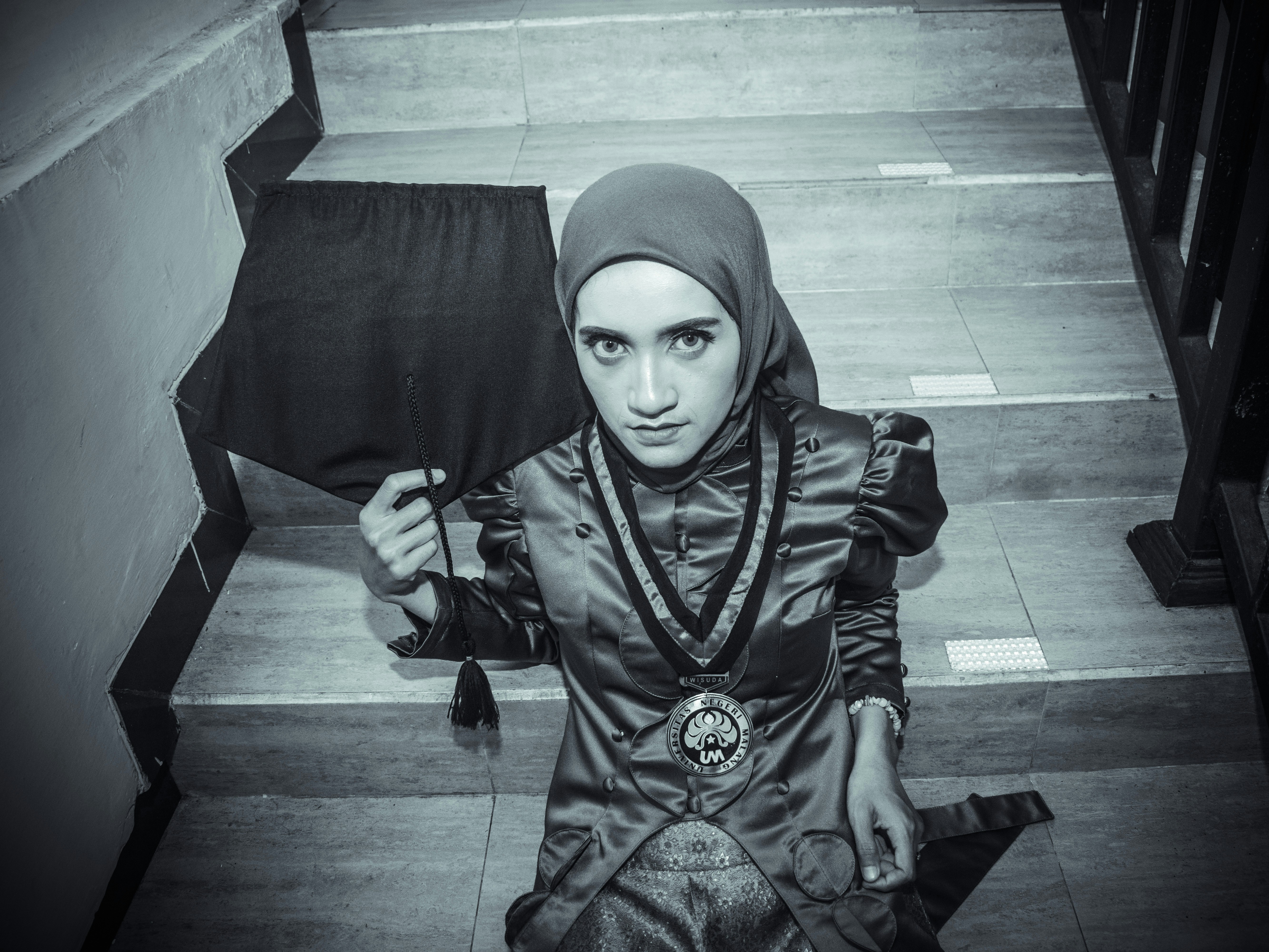 Wanita berjilbab dan gaun formal di tangga