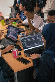 Students working on laptops at a shared desk.