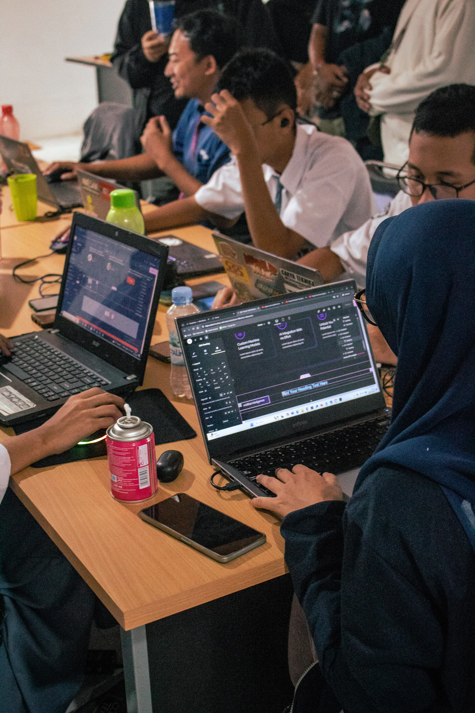 Students coding side by side on laptops at a shared table